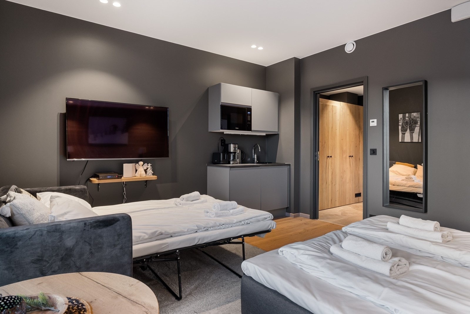 Lite te-kjøkken i hjørnet av stua med microbølgeovn, oppvaskkum og tre skapplasser. Galleribilde