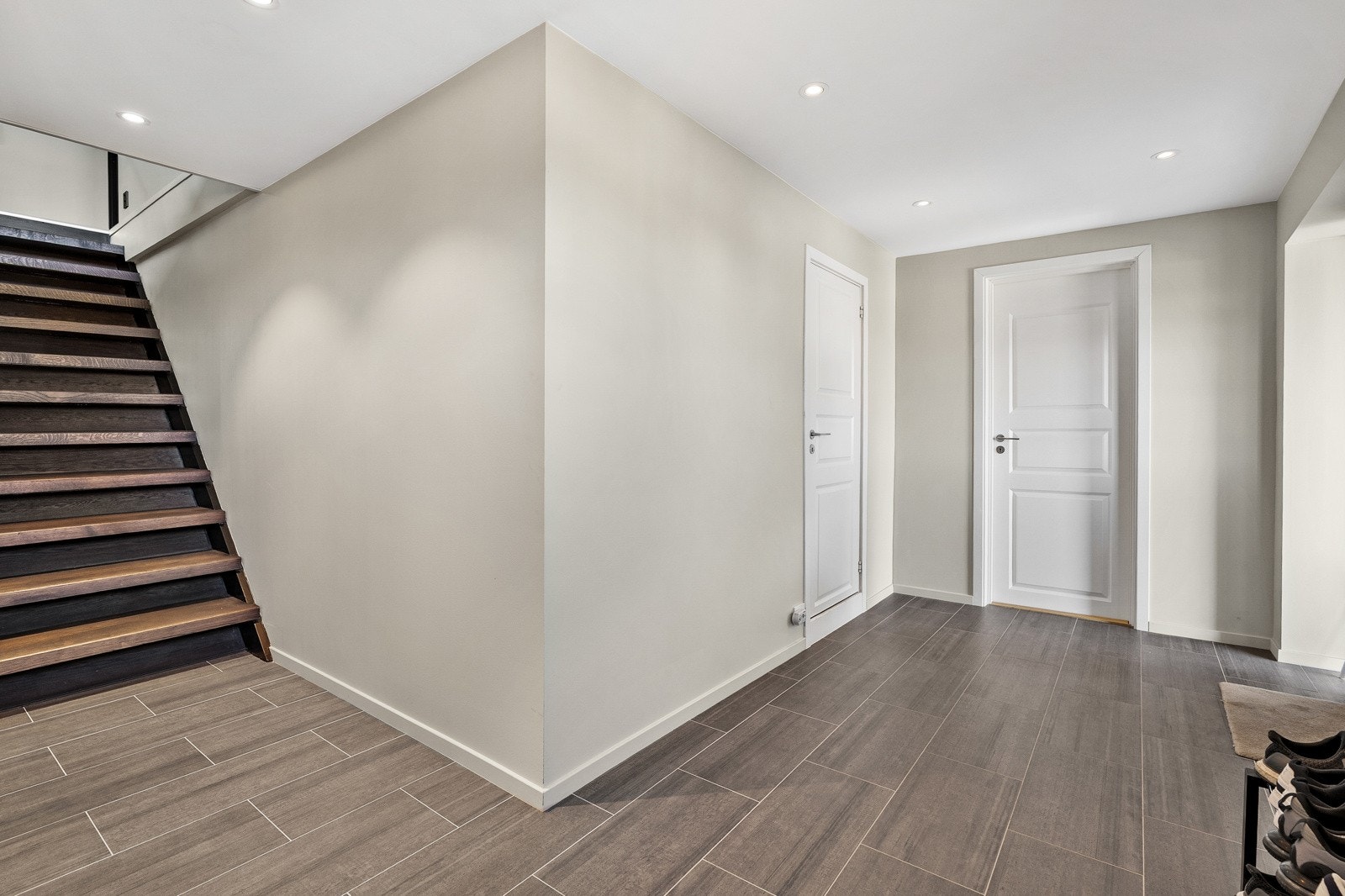 Lys og romslig hall med moderne flislagt gulv og direkte adkomst til flere rom. Galleribilde