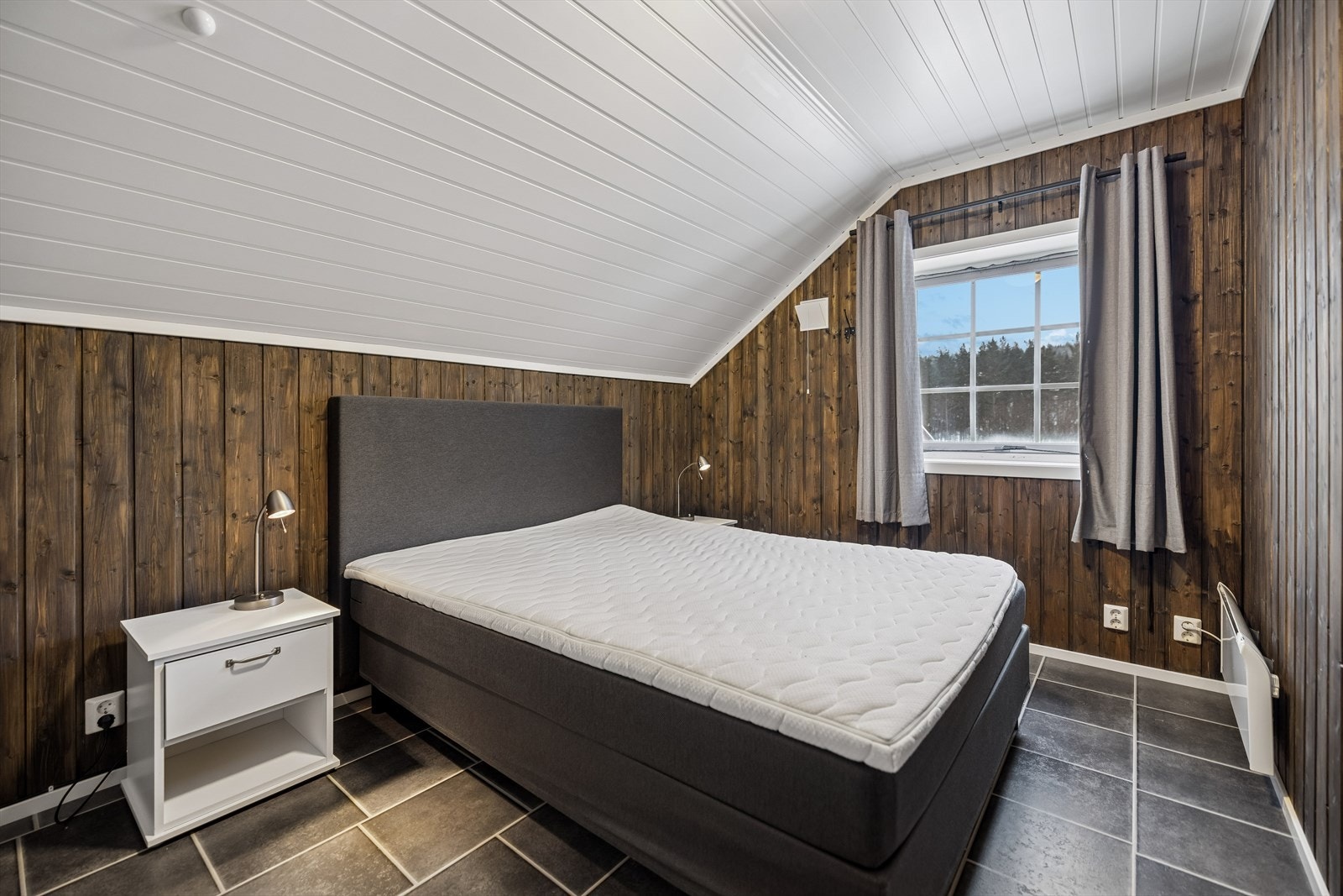 Et av de to ferdigstilte soverommene i andre etasje, med mørkt beiset panel. Galleribilde