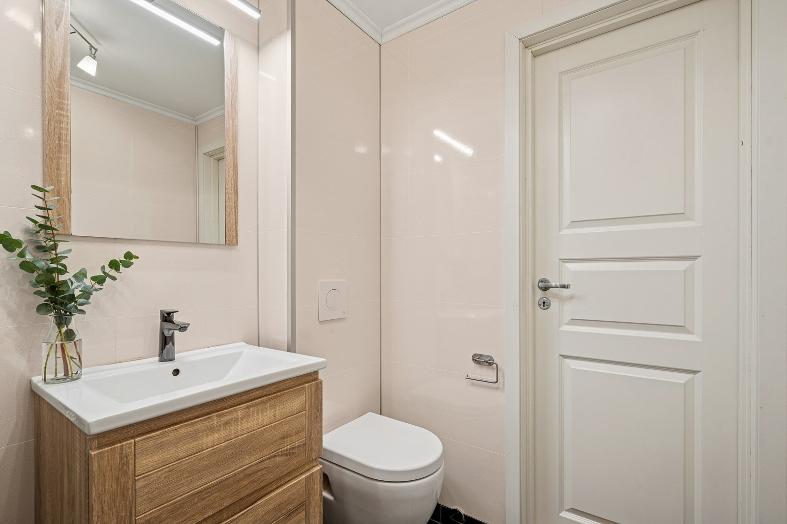 Badet er innredet med baderomsinnredning med nedfelt servant, vegghengt speil, vegghengt toalett og dusjhjørne med glassvegger. Galleribilde