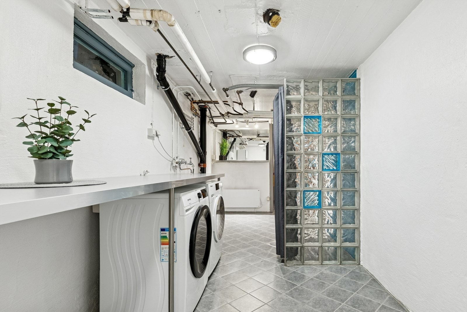 Kjelleren har et stort vaskerom med arbeidsbenk, dusjnisje og opplegg for vaskemaskin. Galleribilde