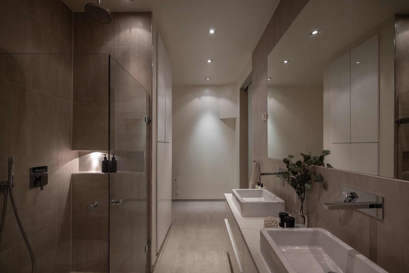 Badet har praktisk dusjhjørne med innfellbare glassdører og innebygget dusjarmatur i vegg med regndusj og hånddusj, innfliset badekar med hånddusj og vegghengt toalett fra Villeroy & Boch. Galleribilde