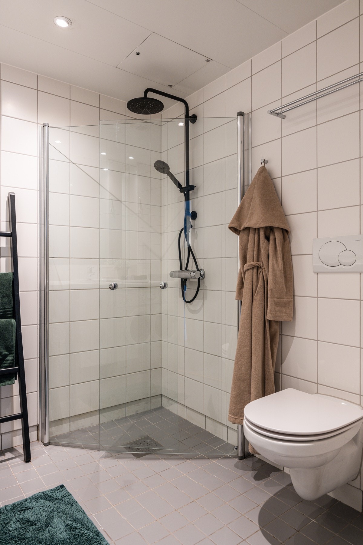 Baderommet er også utstyrt med dusjhjørne med innfellbare glassdører og sort armatur med både hånd- og regnfallsdusj, samt vegghengt toalett. Galleribilde