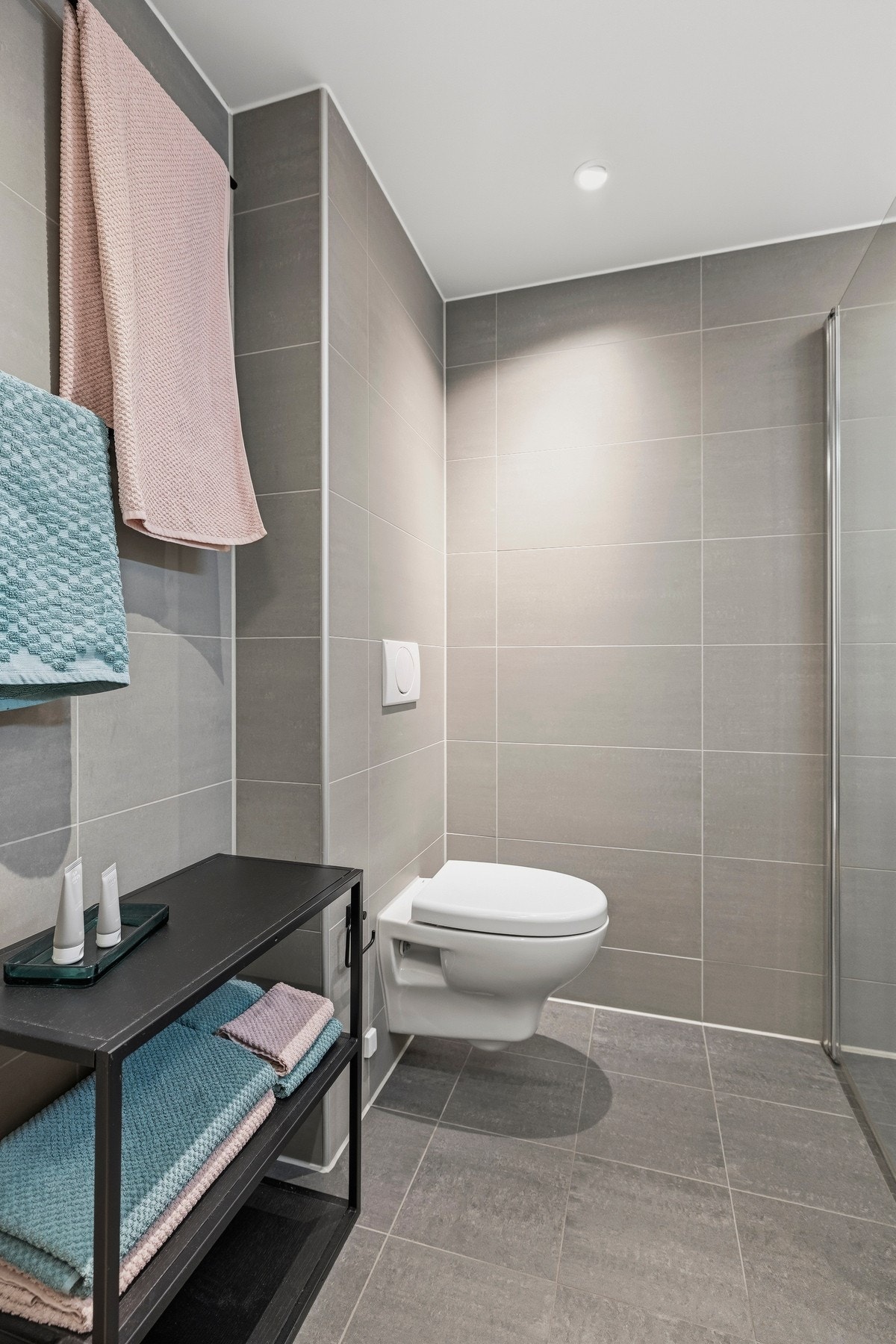 Innredningen inkluderer skap med glatte fronter, servant, veggfestet klosett og dusj på gulv Galleribilde