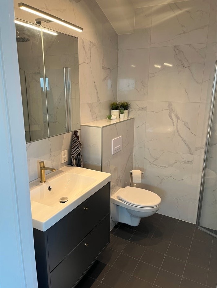 Helfliset bad med vegghengt toalett, stort servant- og speilskap. Dimmbar belysning. Galleribilde