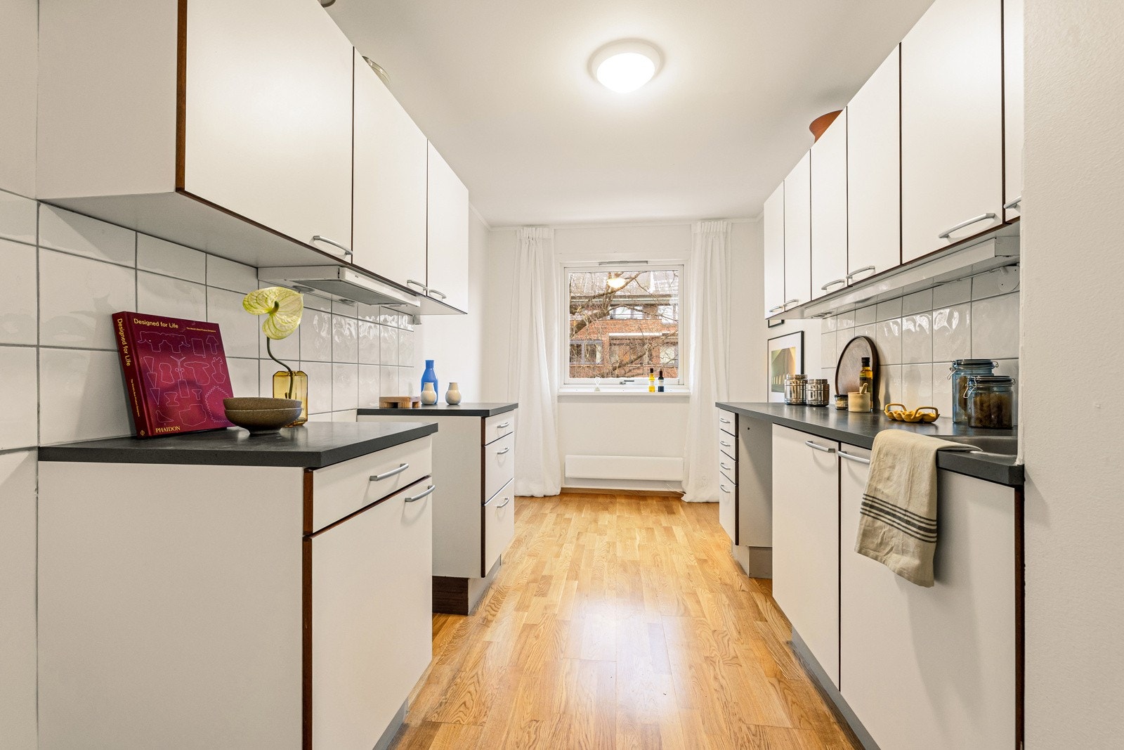 Lyst kjøkken i eget rom, med profilerte fronter og laminert benkeplate. Galleribilde