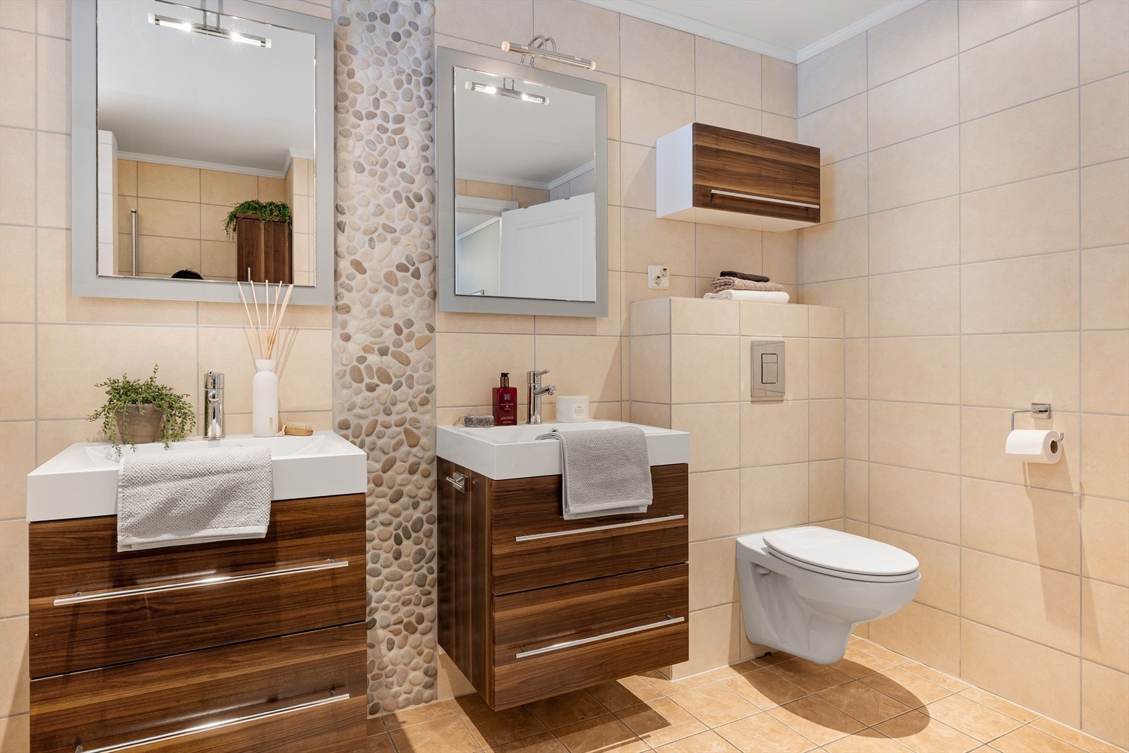 To baderomsinnredninger med skuffer og ovenpåliggende servanter, speil med belysning over. Baderommet er også utstyrt med vegghengt toalett. Galleribilde