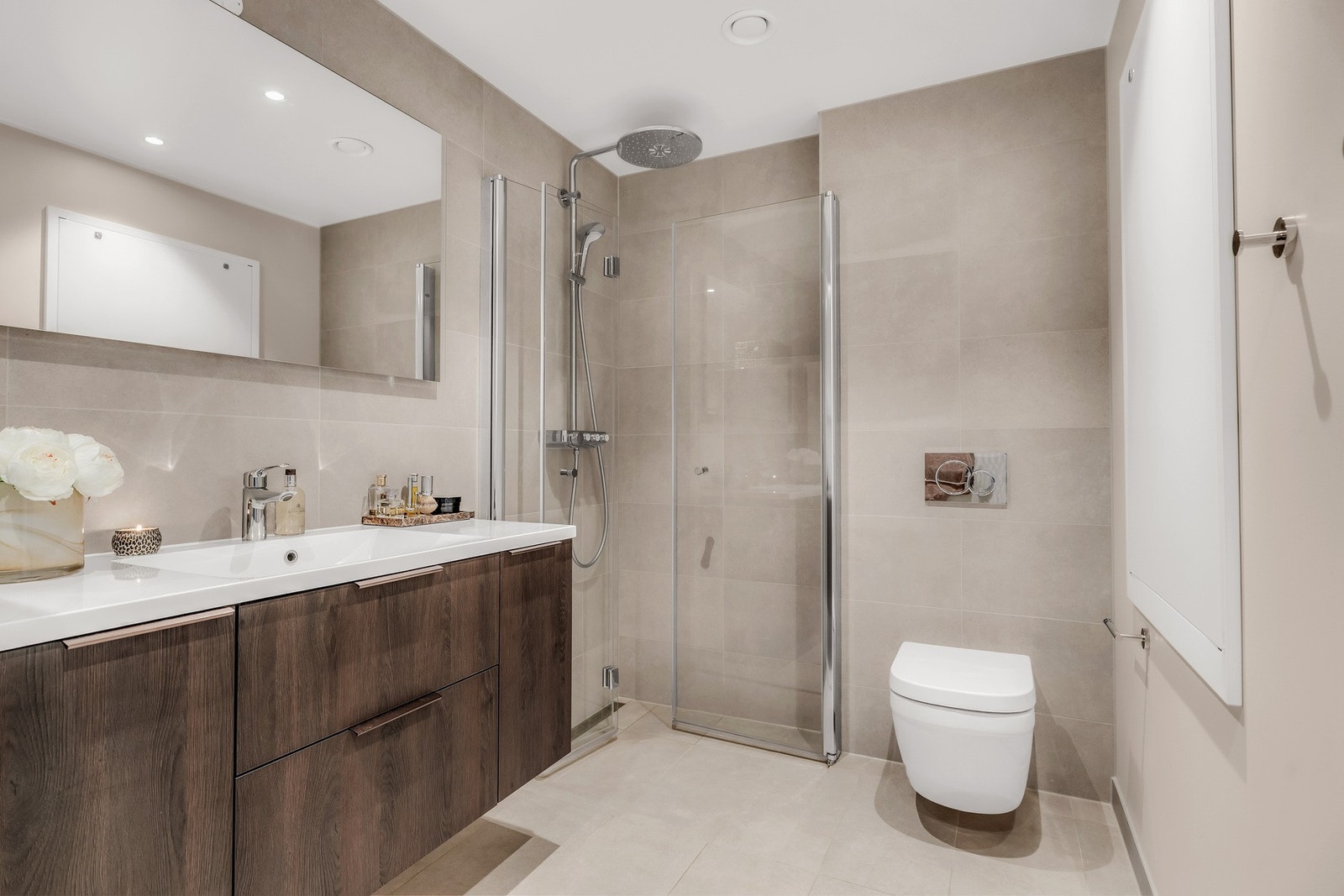 Det andre badet har adkomst fra gang/entré og er utstyrt med servantinnredning og speil, dusjnisje med glassdører og toalett. Både dusjarmatur og toalett er tilvalg fra leverandør Grohe og er montert på begge badene. Galleribilde