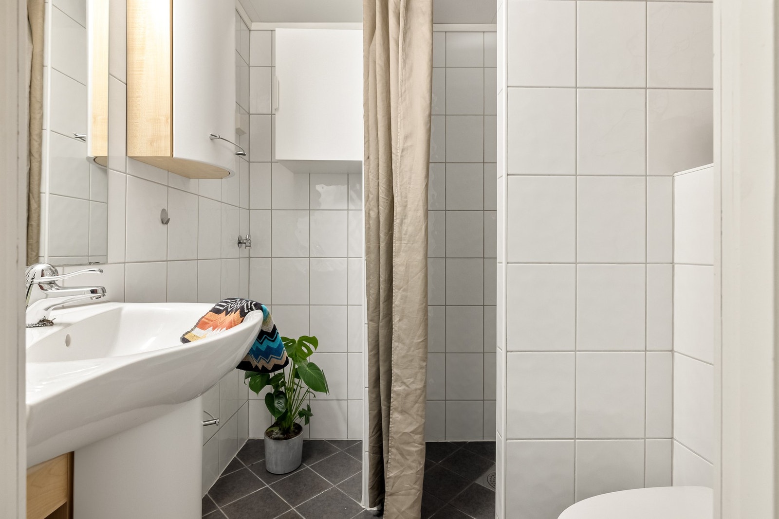 Det er innredet med vegghengt toalett, dusj og baderomsinnredning med servant, speil og belysning. Galleribilde