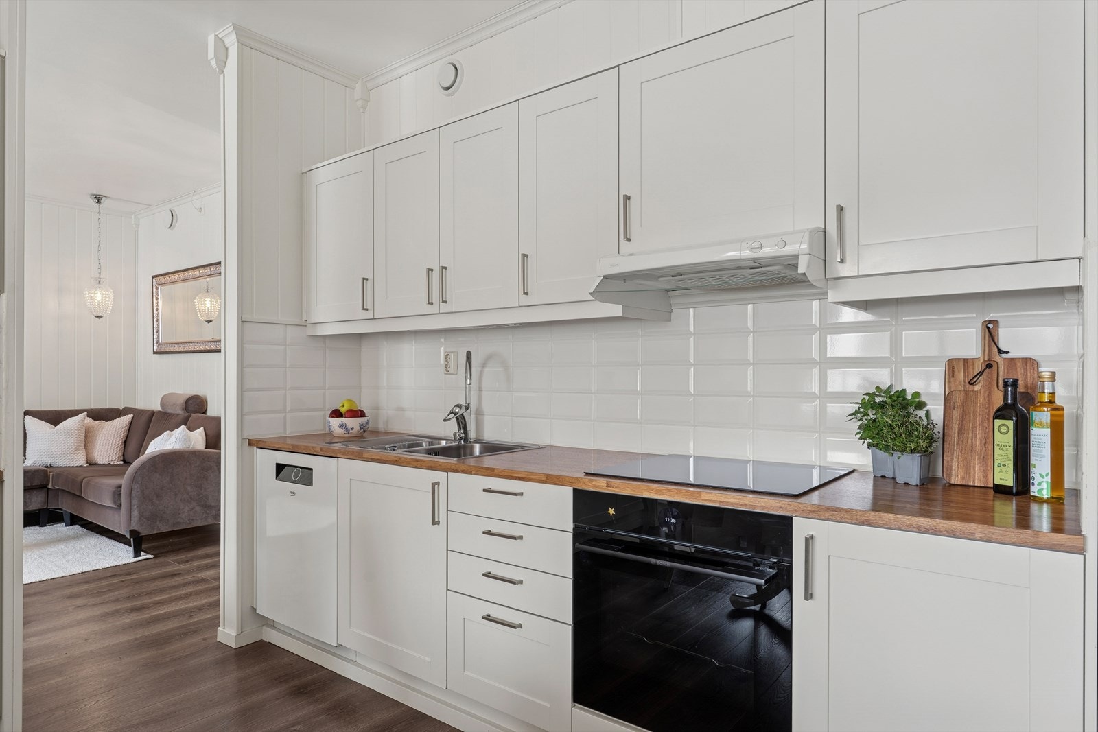 Kjøkkeninnredningen har profilerte hvite fronter og fliser mellom over- og underskap. Galleribilde