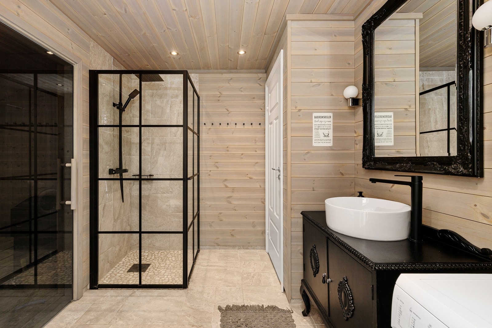 Badet har innredning med frittstående servant, hjørnedusj med glassvegger, vegghengt toalett og opplegg for vaskemaskin. Galleribilde