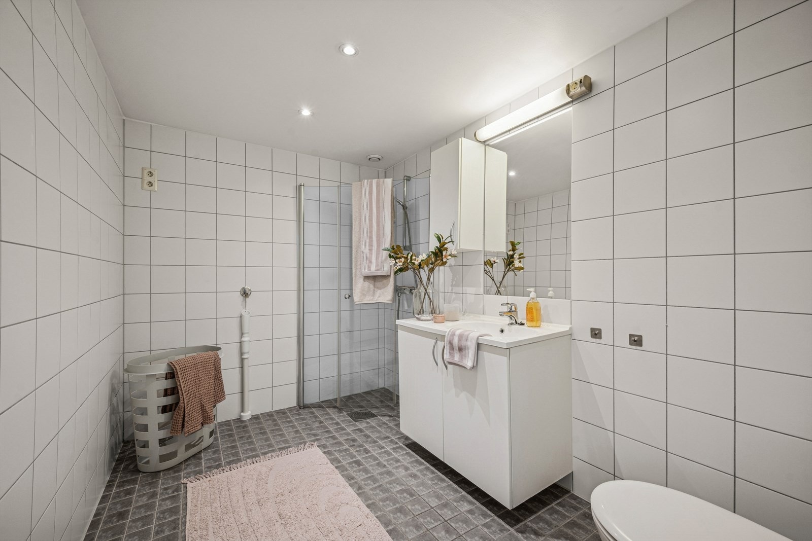 Flislagt bad med varmekabler i gulv. Praktisk innredet med servant, toalett og dusjløsning. Det er opplegg for vaskemaskin. Galleribilde