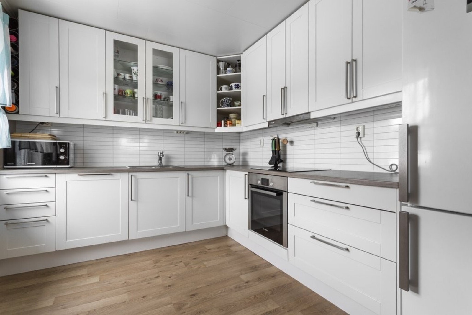 Lyst og moderne kjøkken med integrert steketopp, komfyr og oppvaskmaskin. Moderne uttrykk med pene overflater og god arbeidsplass. Galleribilde