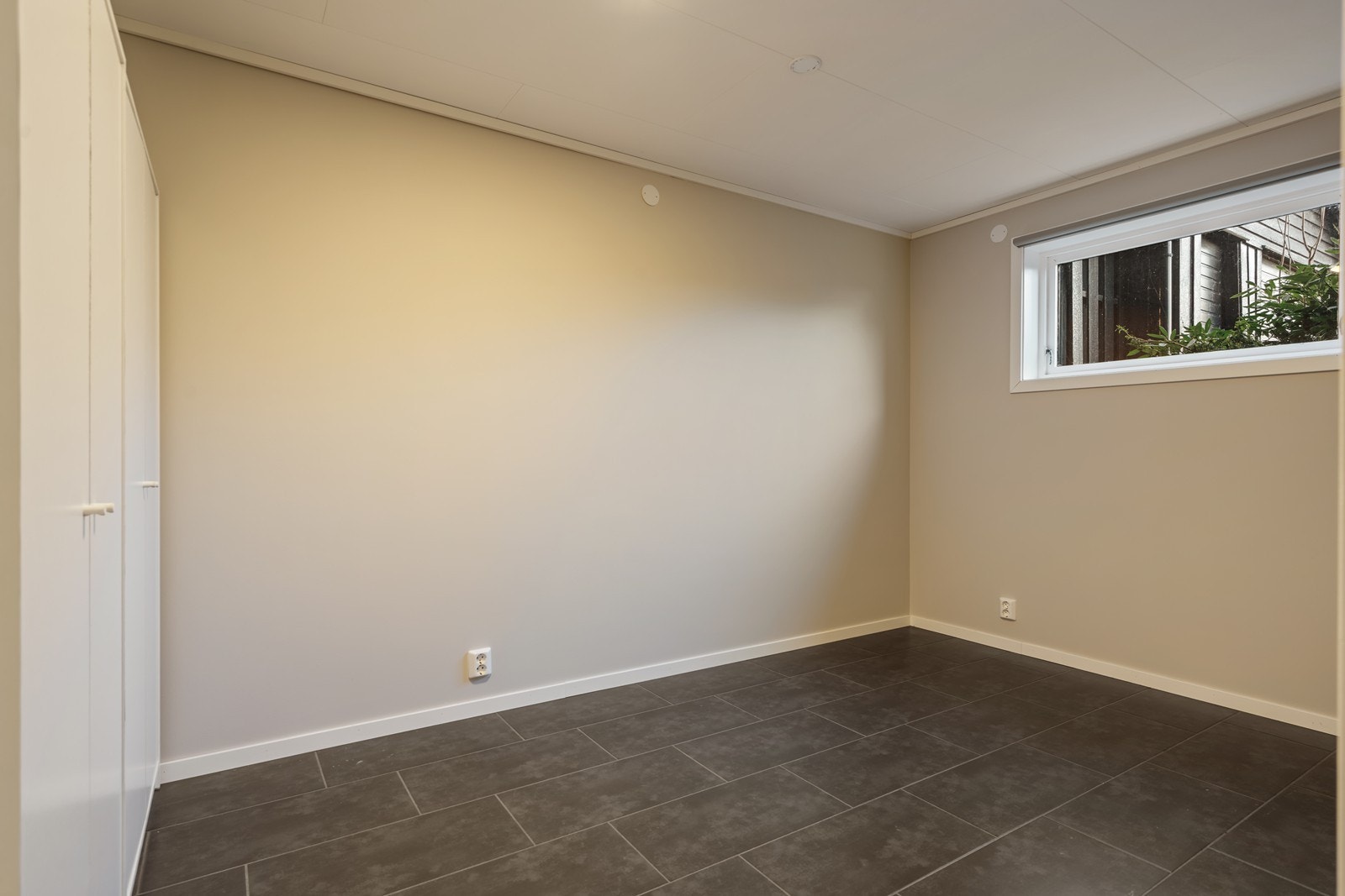 Soverom med rullegardin i vindu, fliselagt gulv med varmekabler, to doble garderobeskap. Galleribilde