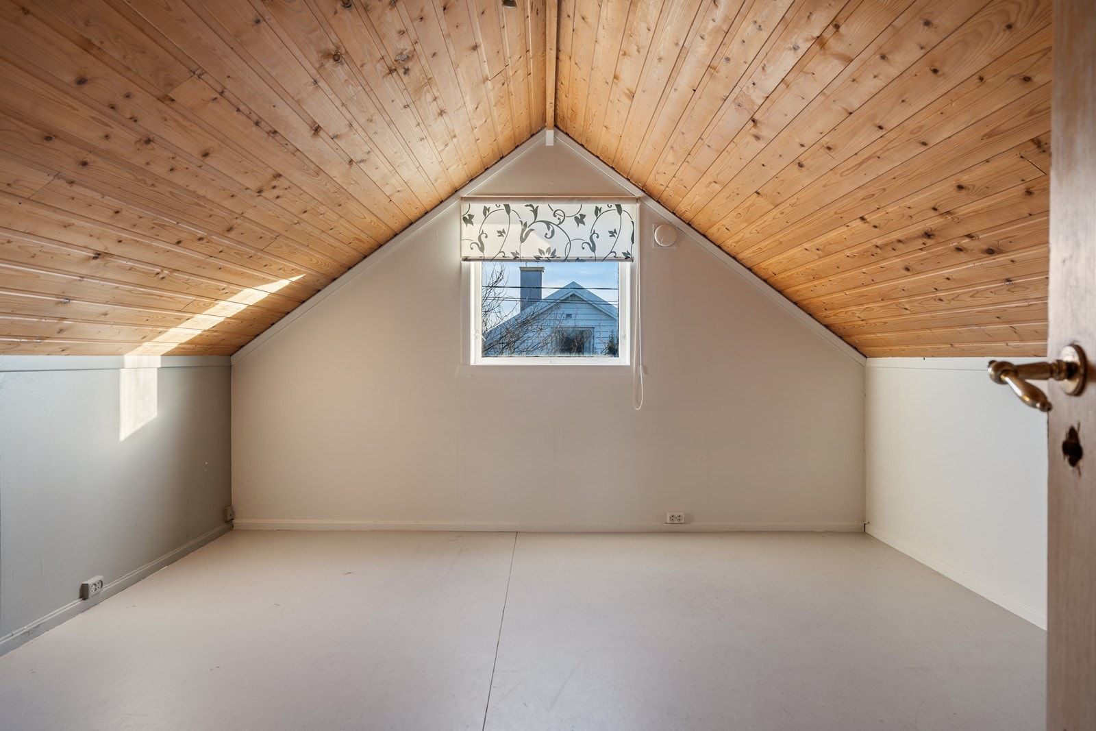 Stort soverom med plass til både dobbeltseng, skrivepult og sofagruppe. Belegg på gulv, umalt panel på skråtak og tapetserte vegger. Galleribilde