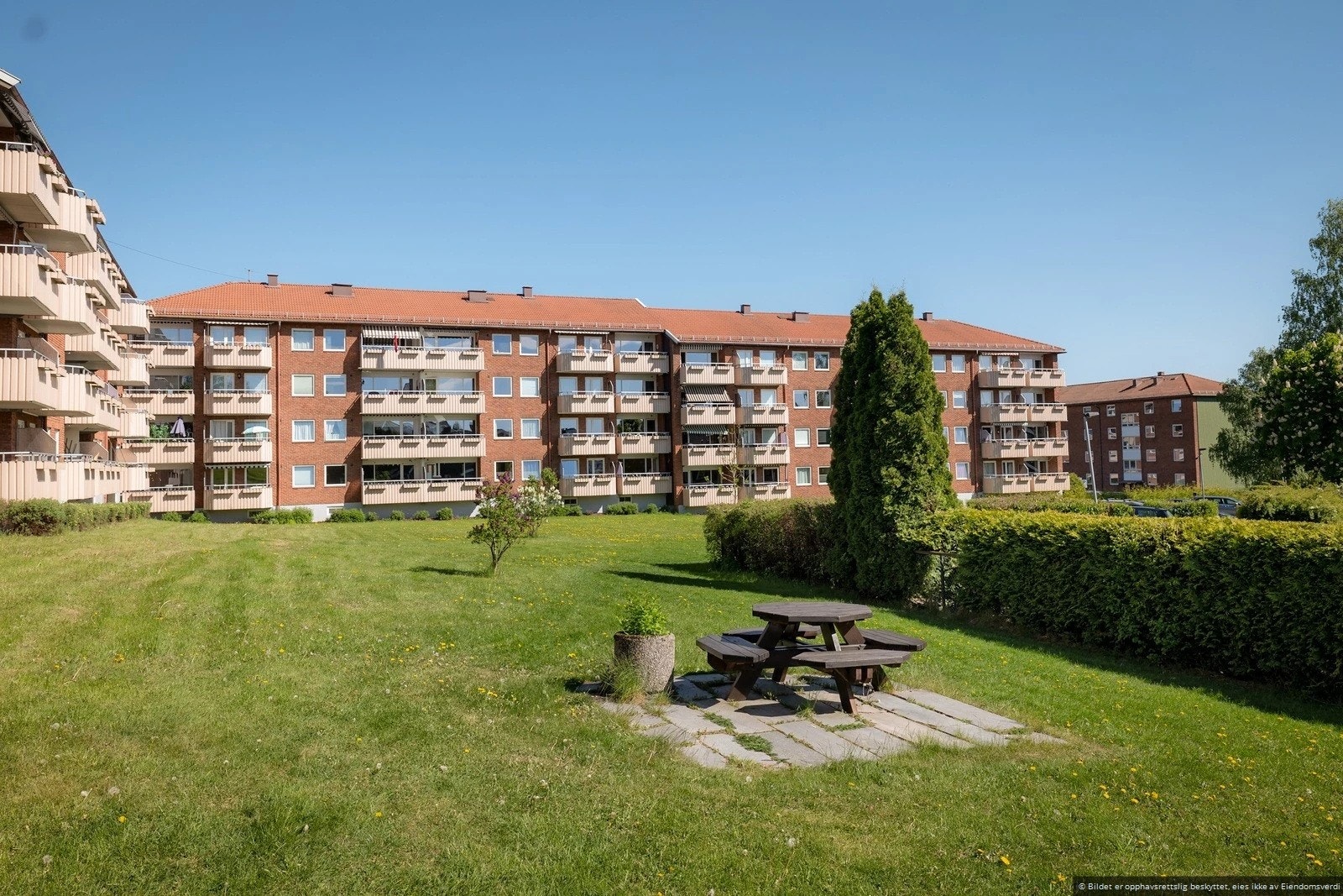 Tomten er pent opparbeidet med gressplen, diverse beplantning og asfaltert adkomst til bebyggelsen. Galleribilde