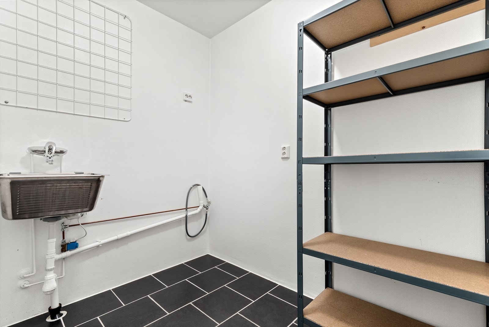 Fra kjøkkenet er det inngang til en praktisk bod med vaskekar og opplegg for vaskemaskin, der det også er montert vannstopper for ekstra trygghet og funksjonalitet. Galleribilde