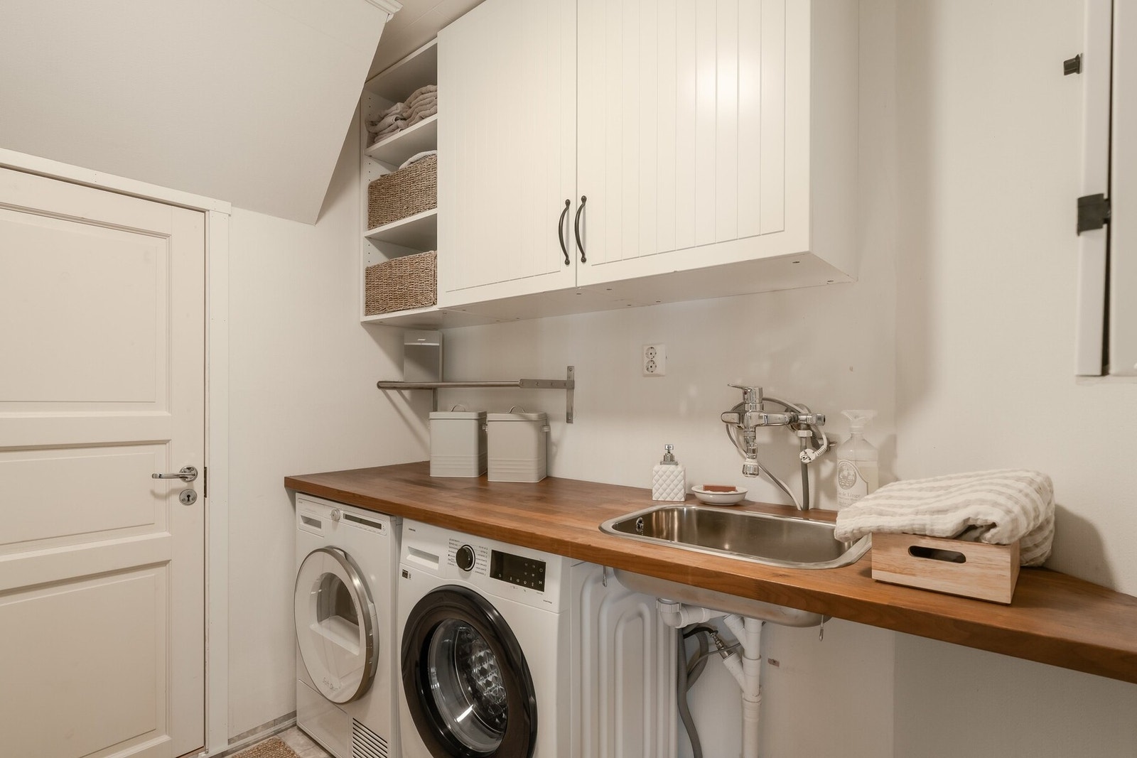 Over benken med utslagsvask er det praktiske skap og hyller. Det er også en bod tilknyttet vaskerommet under trappeoppgang, som byr på ekstra lagringsplass. Galleribilde