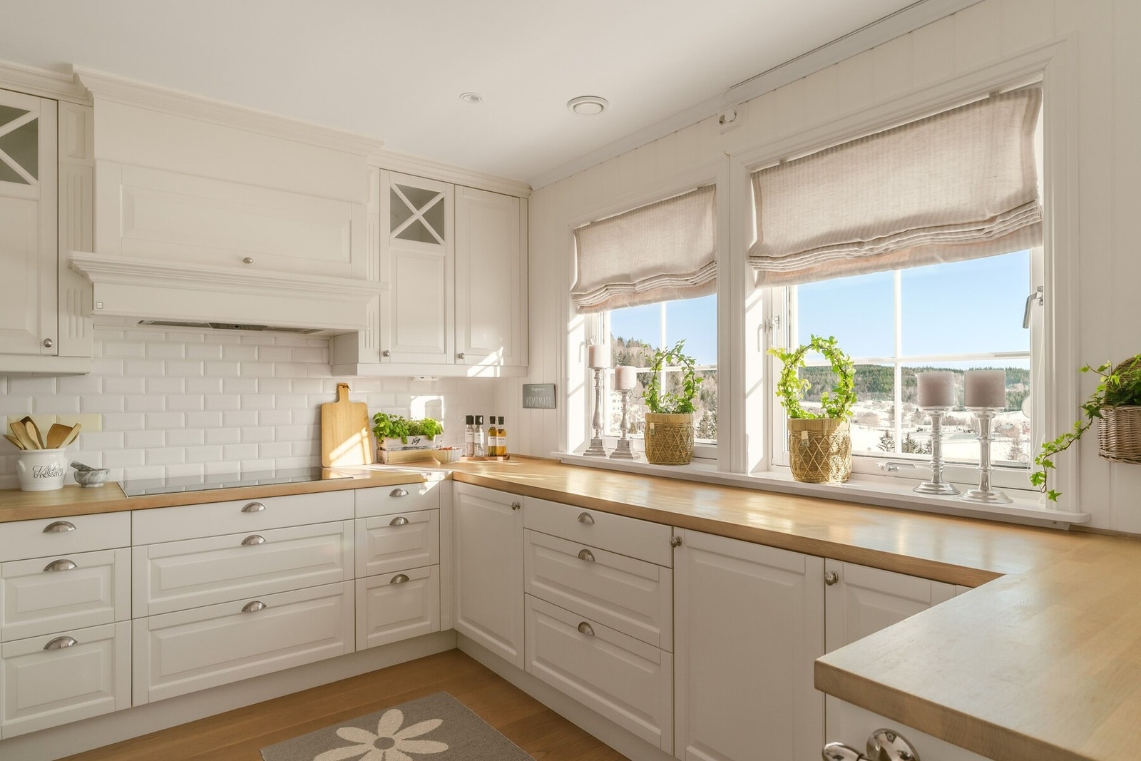 Innredningen er holdt i en lys, helhetlig fargepalett med profilerte fronter i klassisk shaker-stil. De høye overskapene strekker seg helt opp til taket og gir både rikelig med oppbevaringsplass og et eksklusivt, arkitektonisk uttrykk. Galleribilde