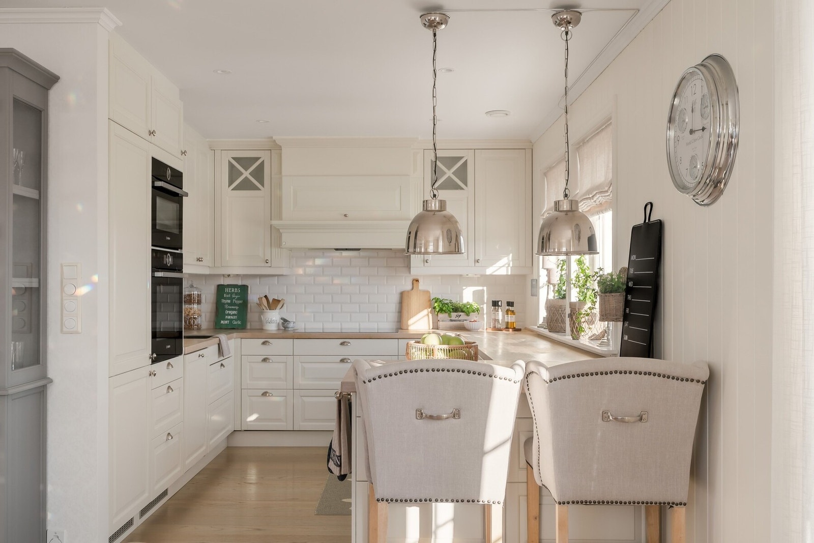 Benkeplate med underlimt vask i lys heltre med naturlig mønster gir kjøkkenet et lunt preg og står i vakker kontrast til de hvite flatene. Detaljer som klassiske knotter i metall forsterker det herskapelige preget. Galleribilde