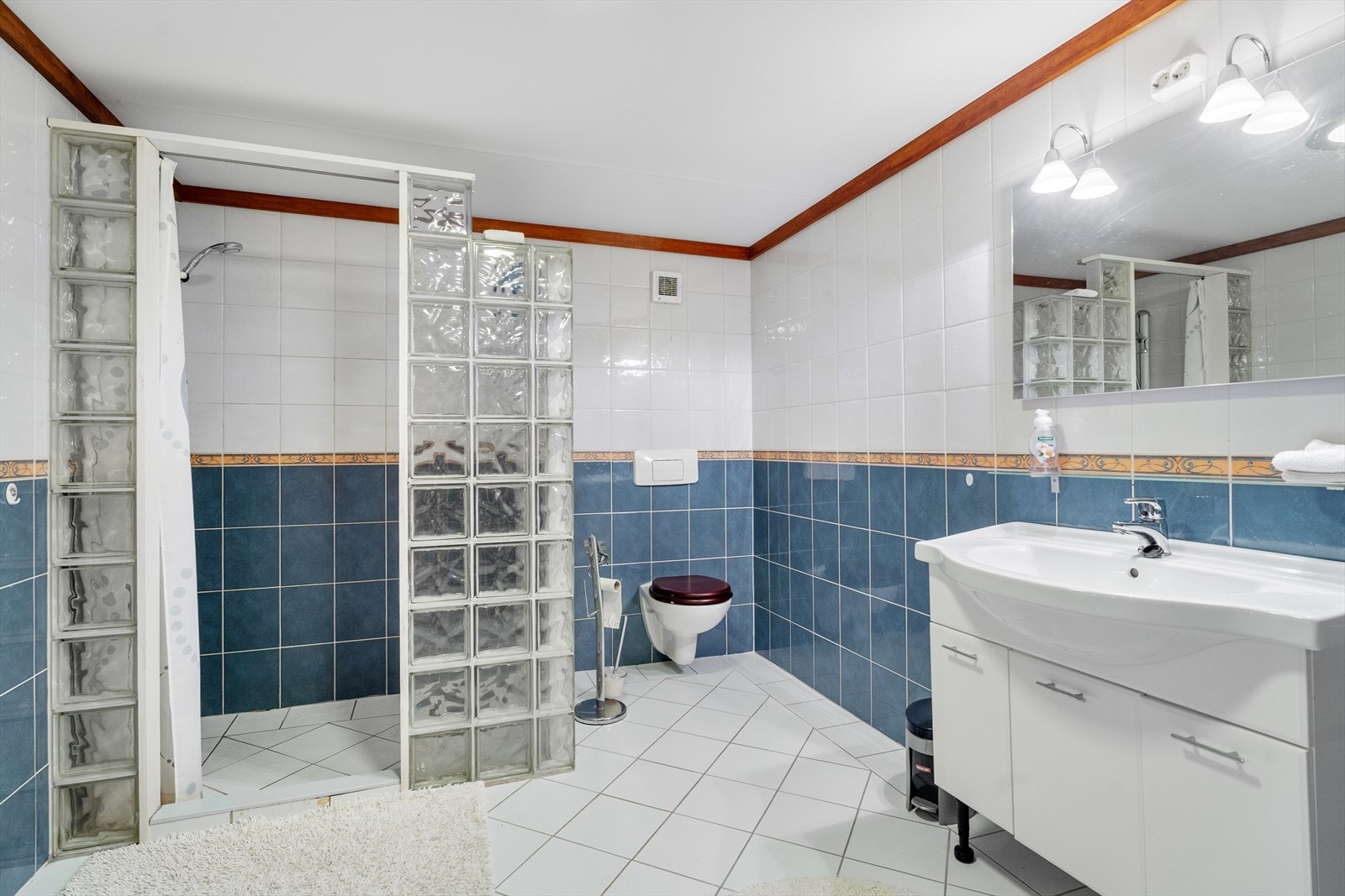 Helfliset og stort bad med stor dusjnisje, vegghengt toalett og innredning med servant Galleribilde