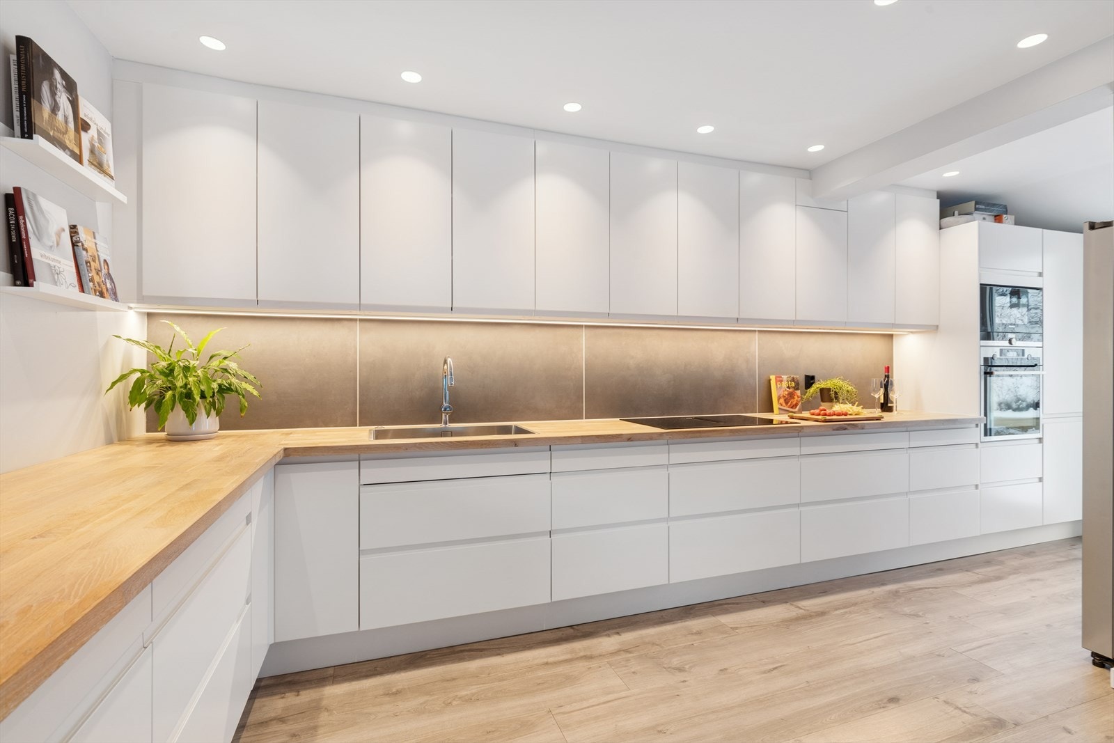 Kjøkkenet har rikelig med skap- og benkeplass, med hvite, glatte fronter. Galleribilde