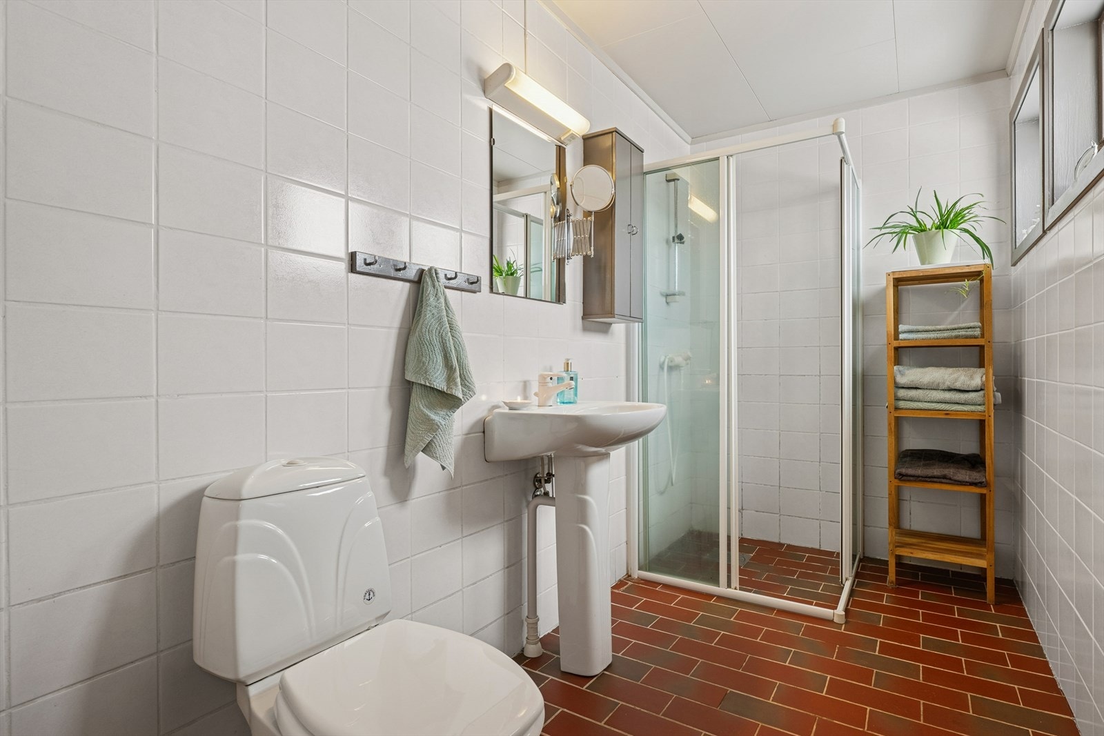 Badet i første etasje. Det er innredet med en avgrenset dusjsone, servant med skap og WC. Gulvet har varmekabler, og en elektrisk avtrekksvifte sørger for ventilasjon. Galleribilde