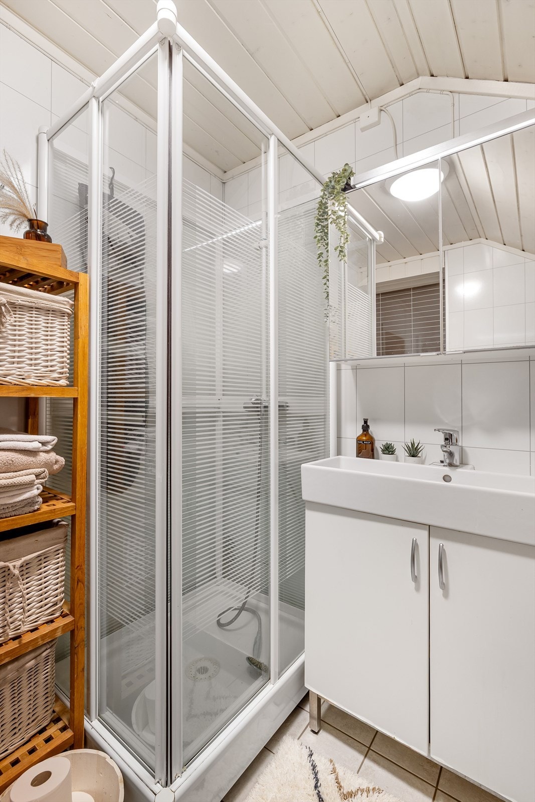 Badet er utstyrt med dujkabinett og servantskap med underskap og heldekkende servant. Over servanten er det speilskap. Galleribilde