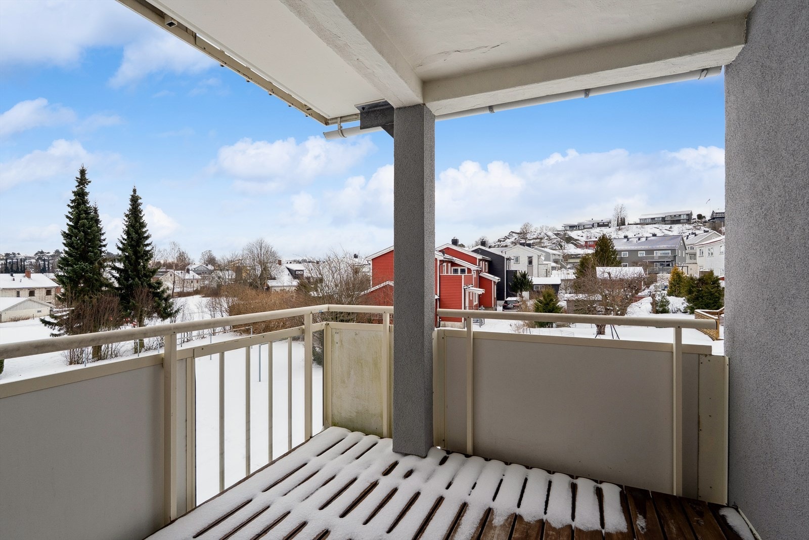 Overbygd balkong med sol og utsikt mot friområde med lekeplass. Galleribilde