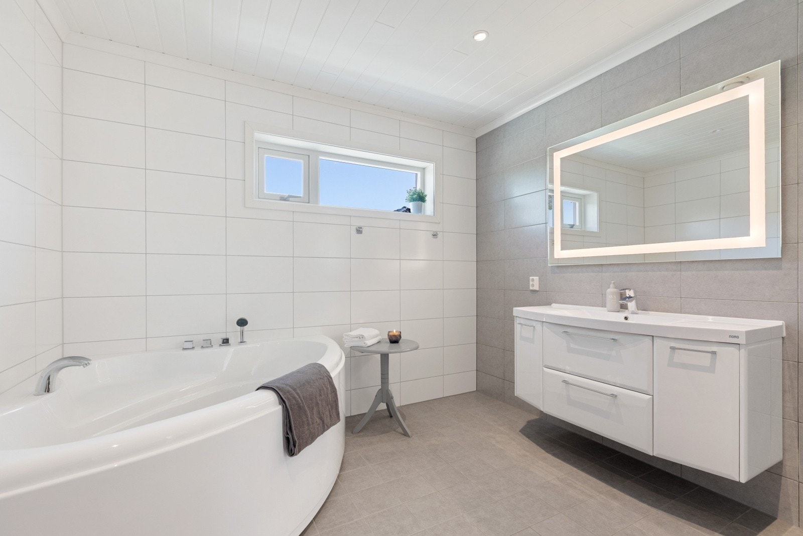 Badet i 2. etasje har flislagt gulv med elektriske varmekabler og flislagte vegger, mens taket består av malt panel som gir rommet et lyst og helhetlig uttrykk. Galleribilde