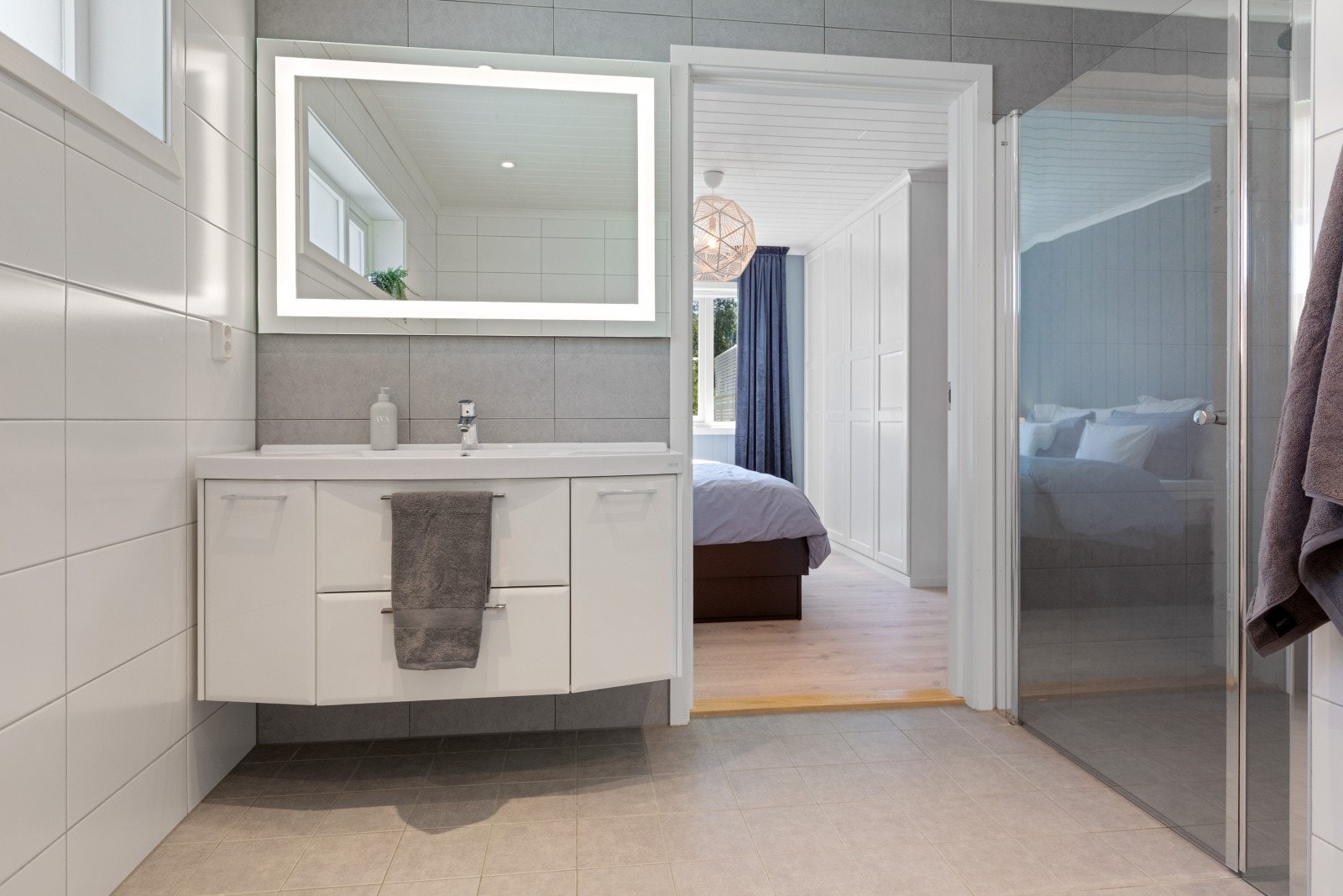 Badet er flislagt og har behagelig gulvvarme. Det er innredet med toalett, dusjnisje med glassdør samt baderomsinnredning med servant og speil, noe som gir et praktisk og funksjonelt rom. Galleribilde