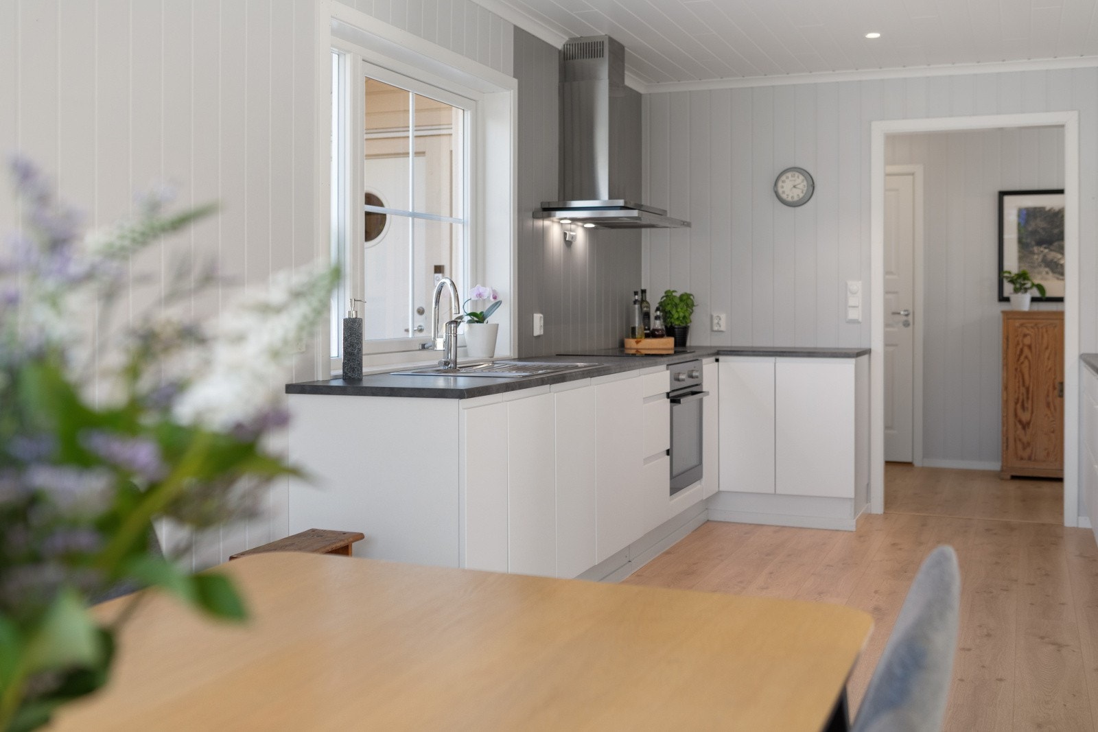 Innredningen har glatte, moderne fronter og en laminert benkeplate med nedfelt oppvaskkum i stål, som gir et stilrent og funksjonelt uttrykk. Galleribilde