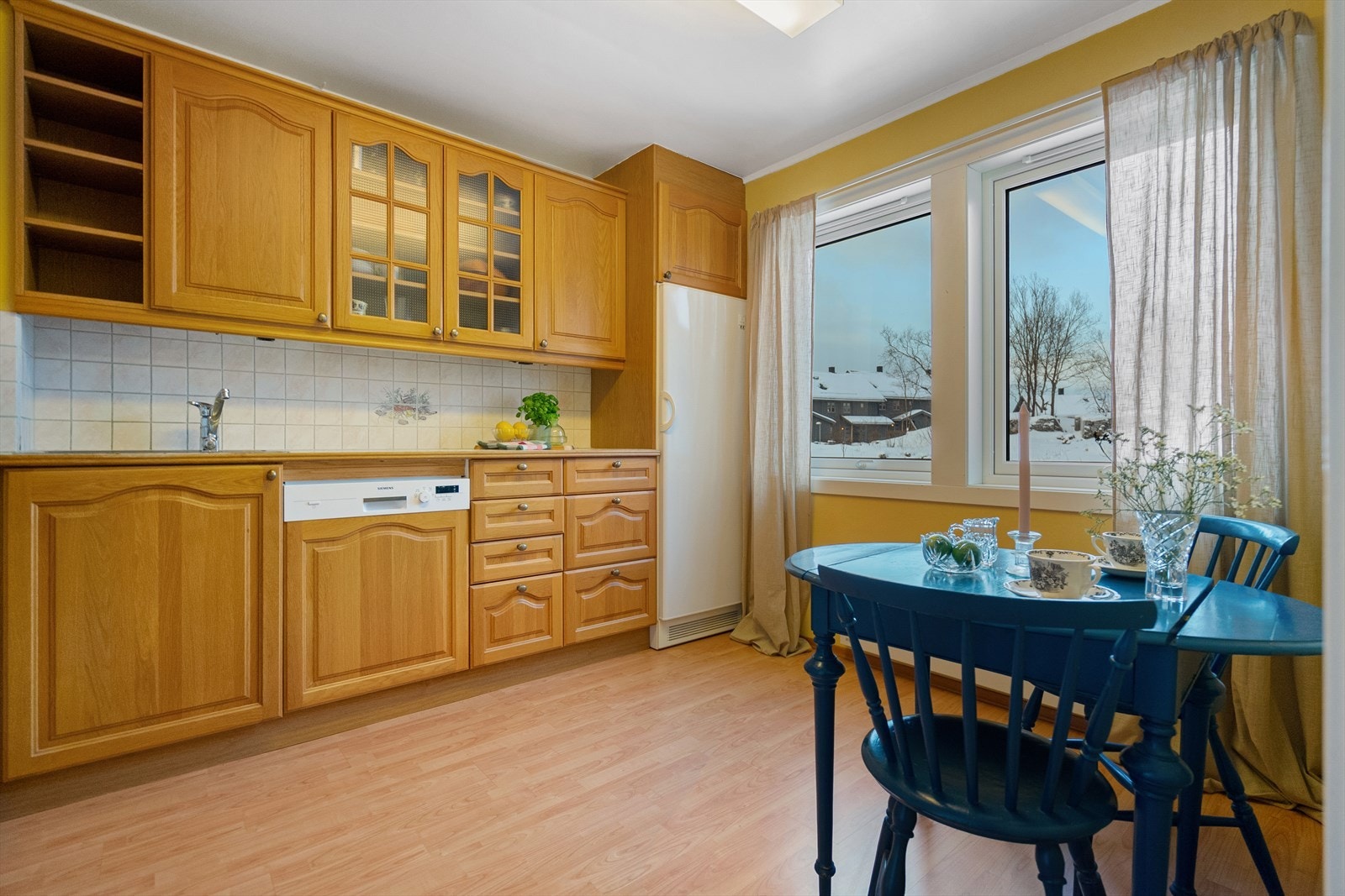 Et romslig kjøkken med klassiske, profilerte eikefronter og flislagt benkeplate - en kombinasjon som gir varme og karakter. Galleribilde