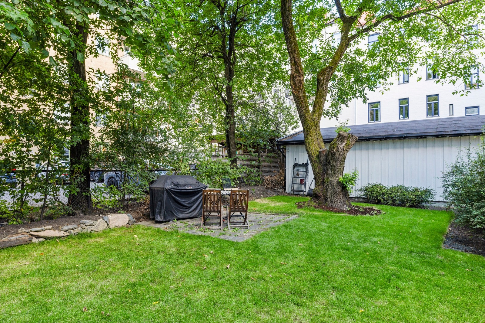 Oppparbeidet med gressplen, beplantning og sittegruppe. Galleribilde