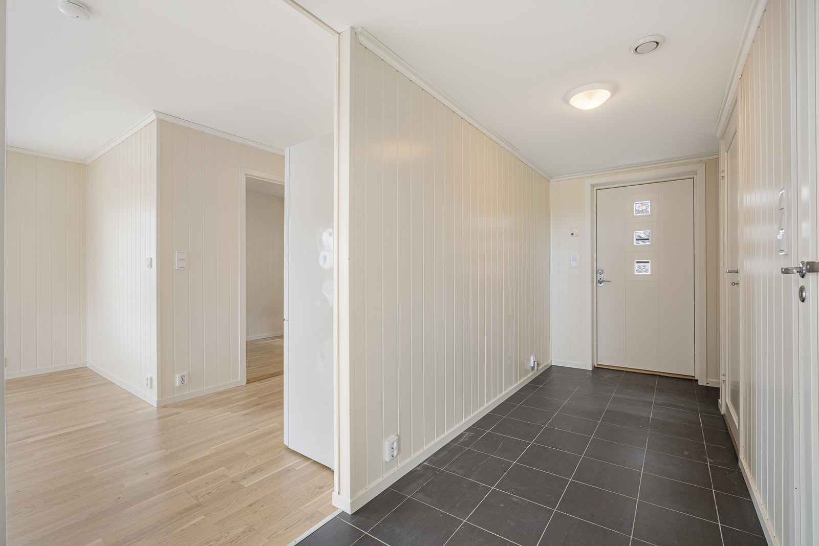 Entreen er malt i en delikat fargetone som står godt til de grå gulvflisene. I en nisje er det en perfekt plass for en garderobeløsning. Galleribilde