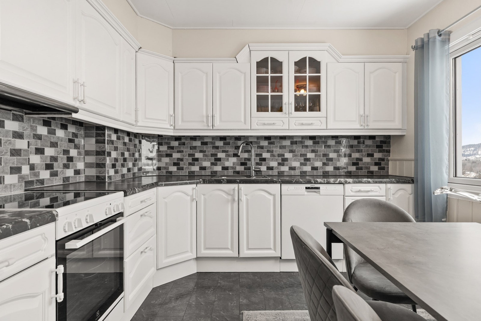 Kjøkkenet er utstyrt med oppvaskmaskin, frittstående komfyr og ventilator i overskap. Galleribilde