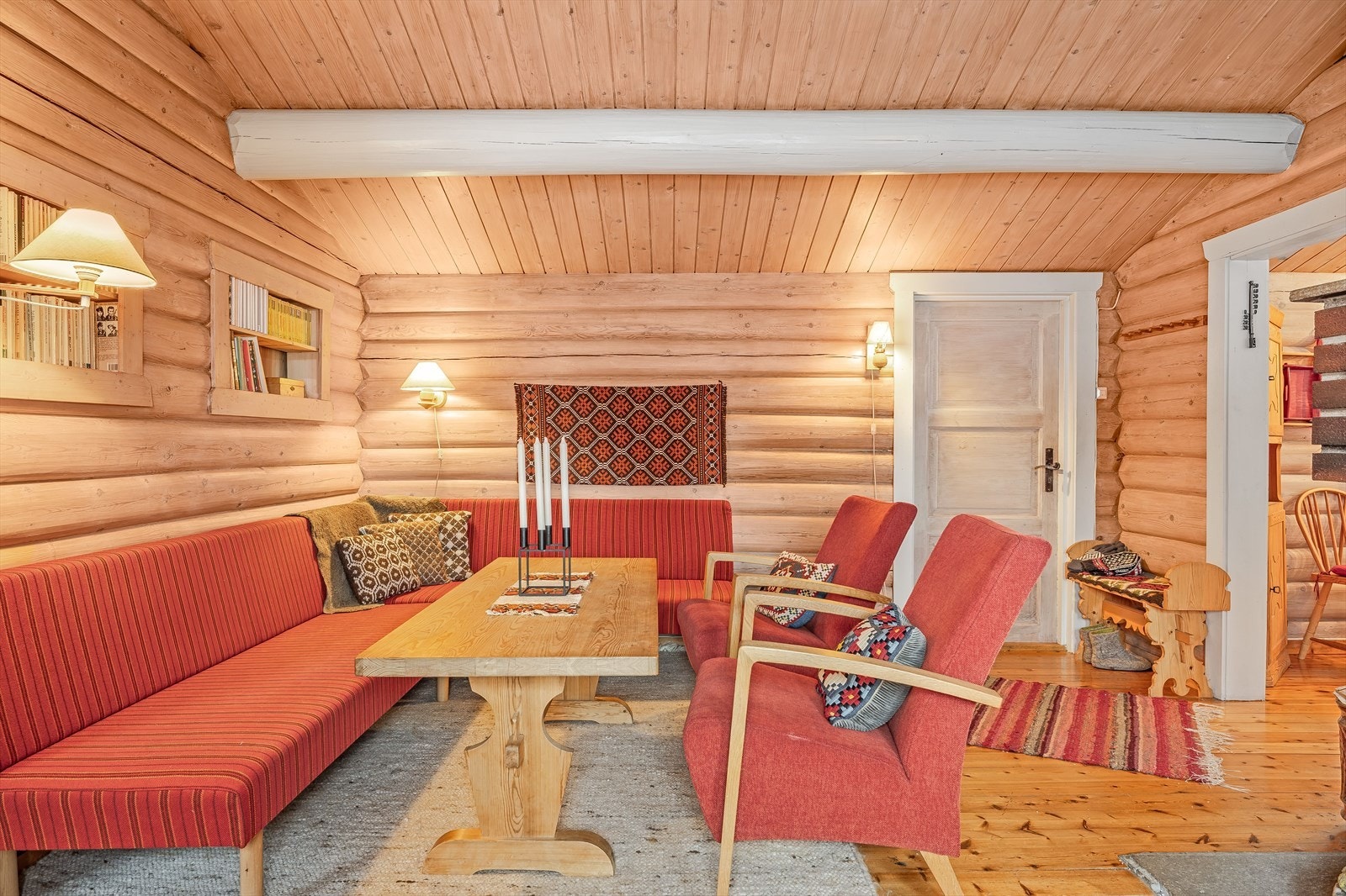 Fin hyttestandard med lakkerte heltre gulv, overflater med laftet tømmer og lysmalte rundstokker i himlingen. Galleribilde