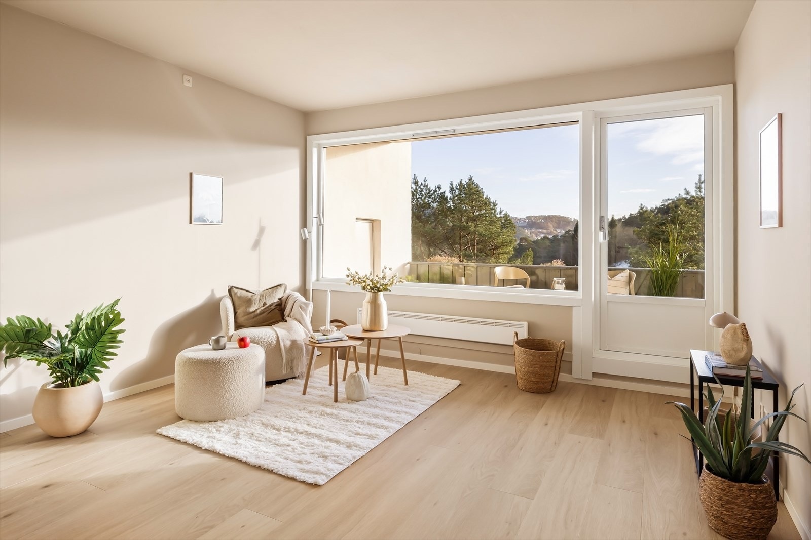 Innbydende stue med en rolig og harmonisk fargepalett. Veggene er malt i en dus, varm beige tone som sammen med det lyse tregulvet skaper en moderne og lun atmosfære. Galleribilde