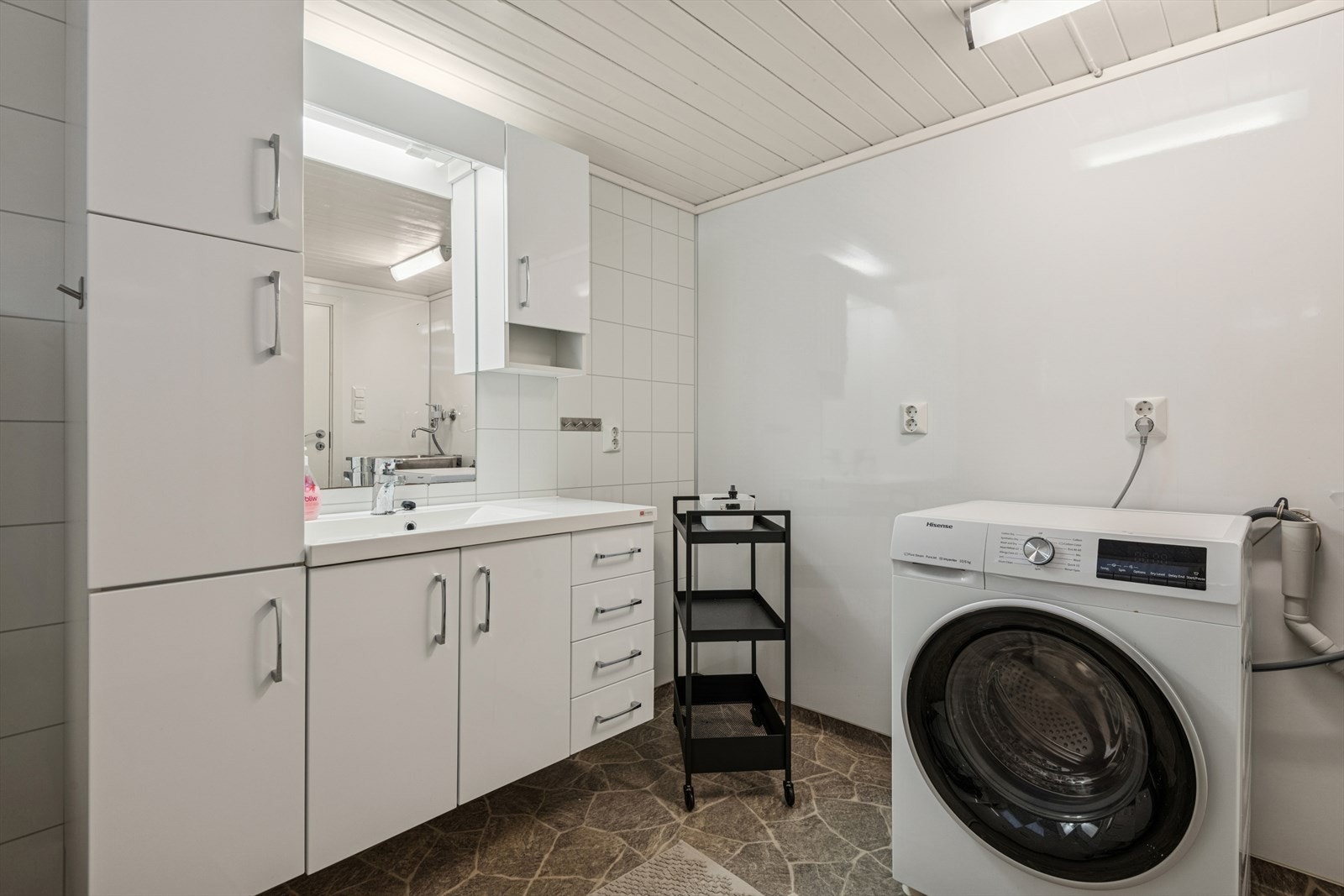 Bad/vaskerom med varmekabler i gulv. Innredet med dusjhjørne med glassvegger, vaskemaskine, utslagsvask, vegghengt toalett og baderomsinnredning med vask. Galleribilde