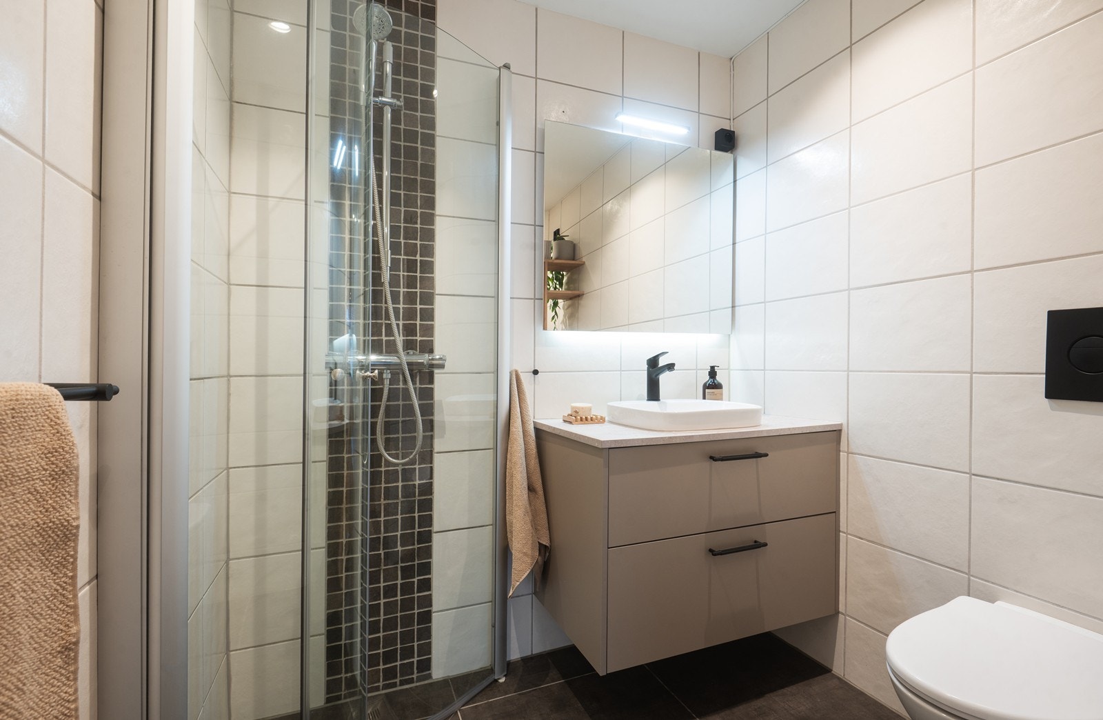 Badeommet har innredning med nedfelt servant, veggmontert toalett, dusjvegger/hjørne og opplegg for vaskemaskin samt elektrisk styrt vifte Galleribilde