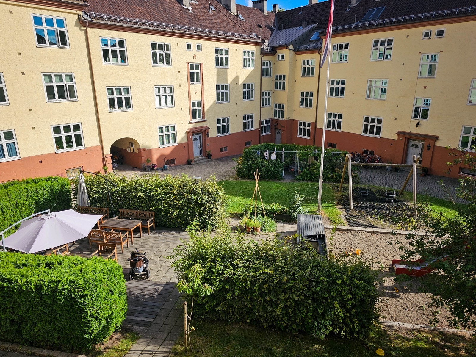 Pent opparbeidet bakgård i grønne, frodige omgivelser med flere sittegrupper Galleribilde