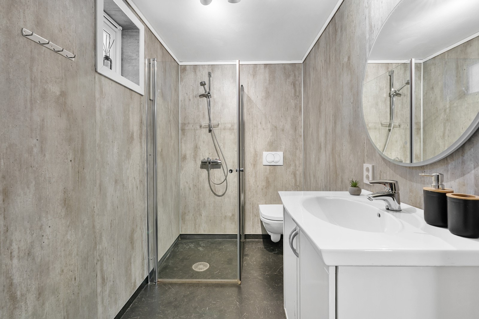 Badet har vegghengt toalett, regulerbare dusjvegger samt vask i seksjon med speil og belysning. Galleribilde