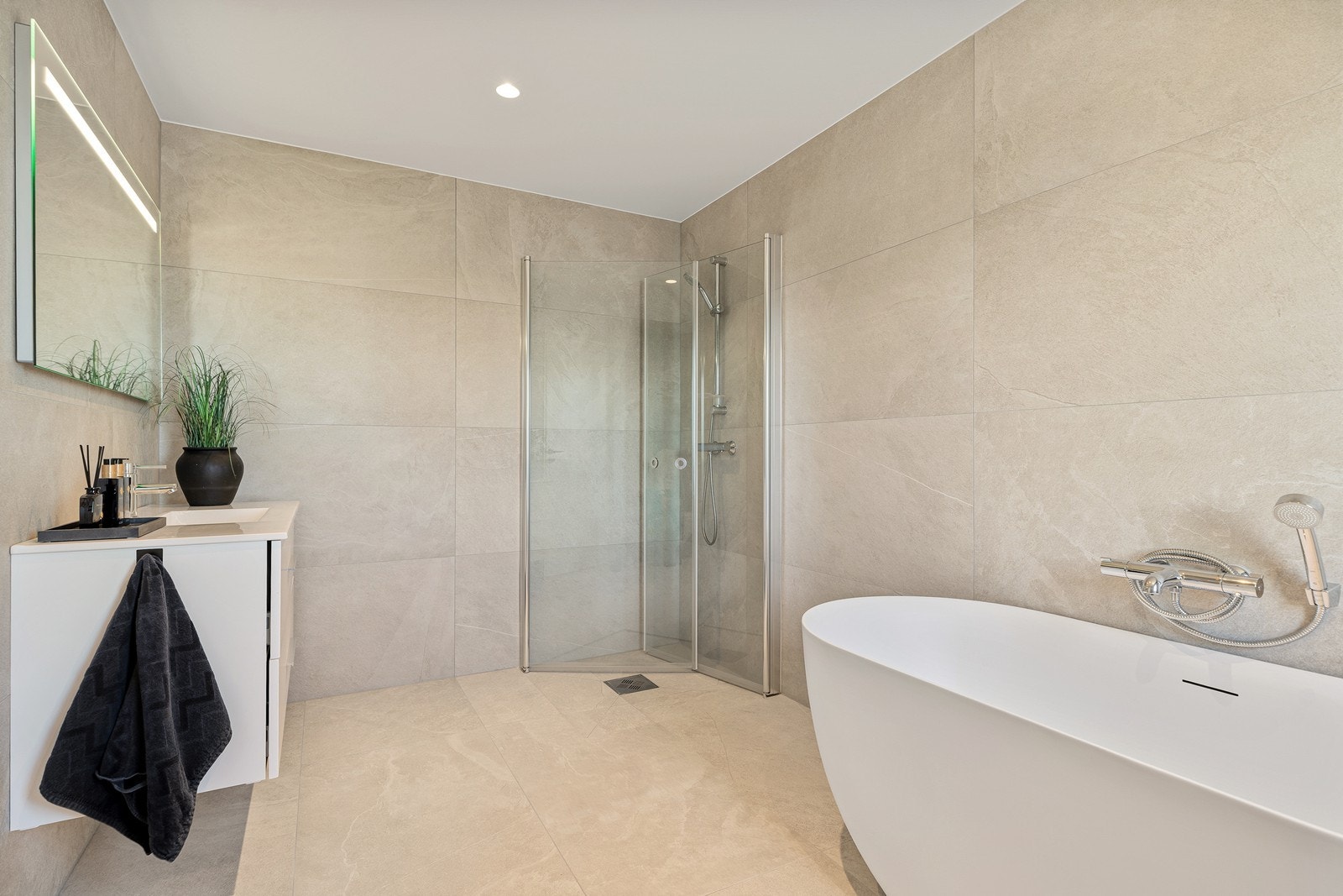 Lekkert baderom med badekar, dusjhjørne, toalett og vegghengt baderomsinnredning Galleribilde