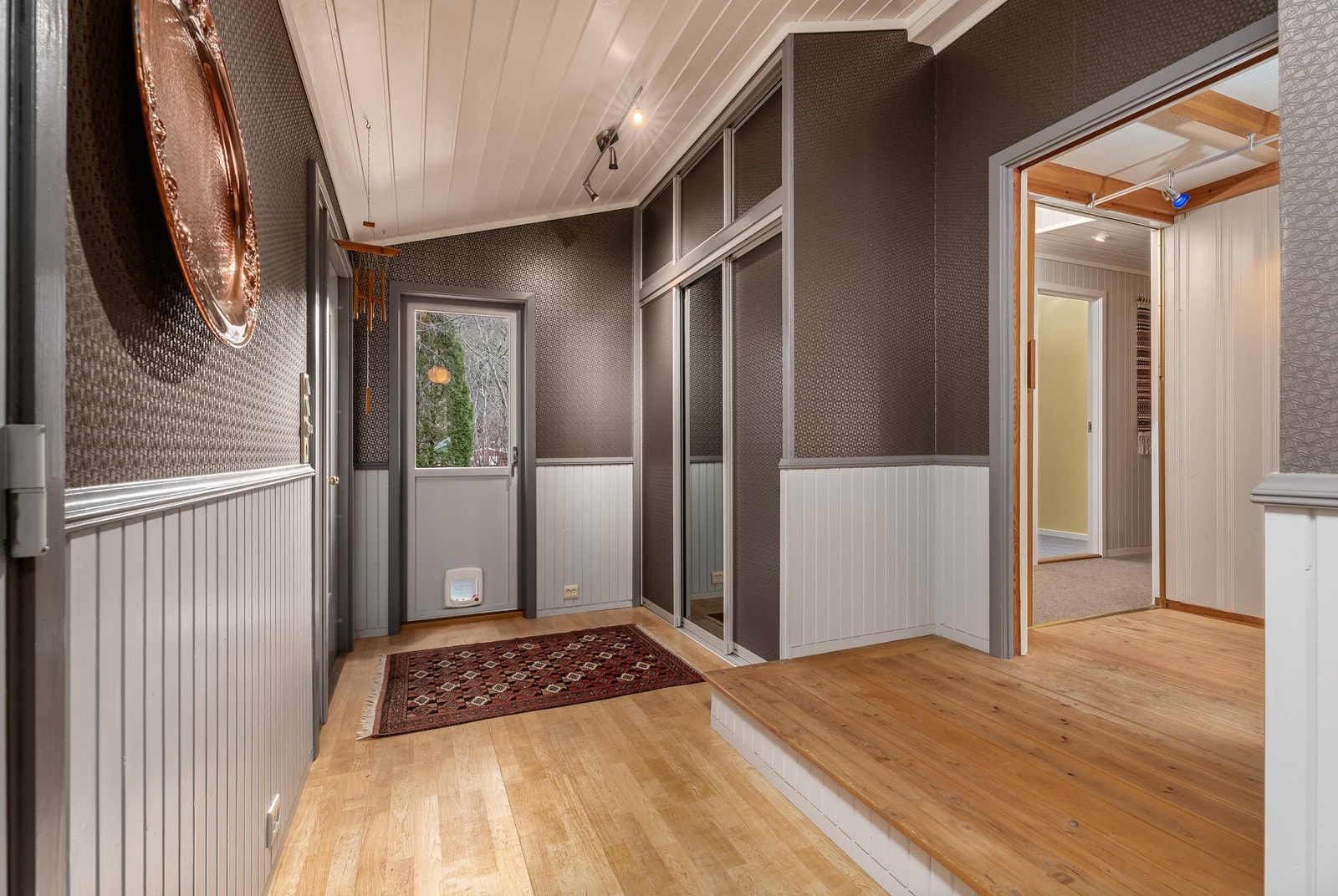 En lun og romslig hall som har praktisk skyvedørsgarderobe. Her er også terrassedør med egen inngang for pus. Galleribilde