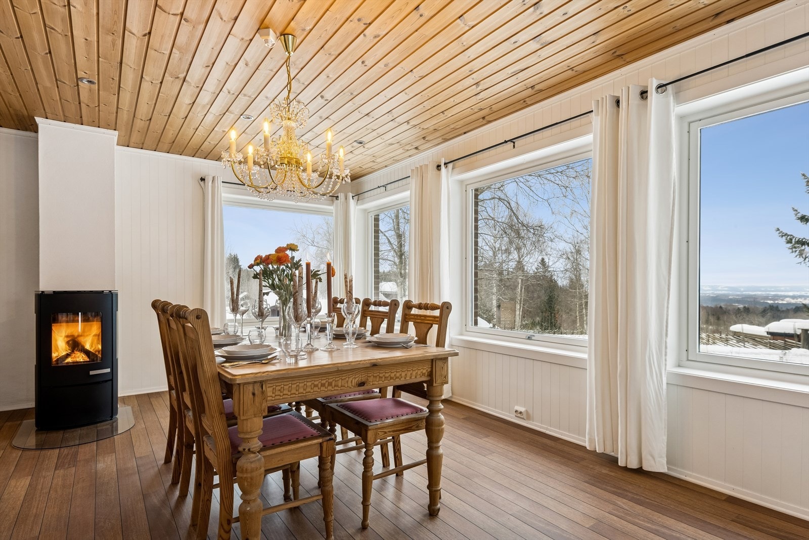 Spisestuen har en moderne peisovn og store vindusflater som gir rikelig med lys. Galleribilde
