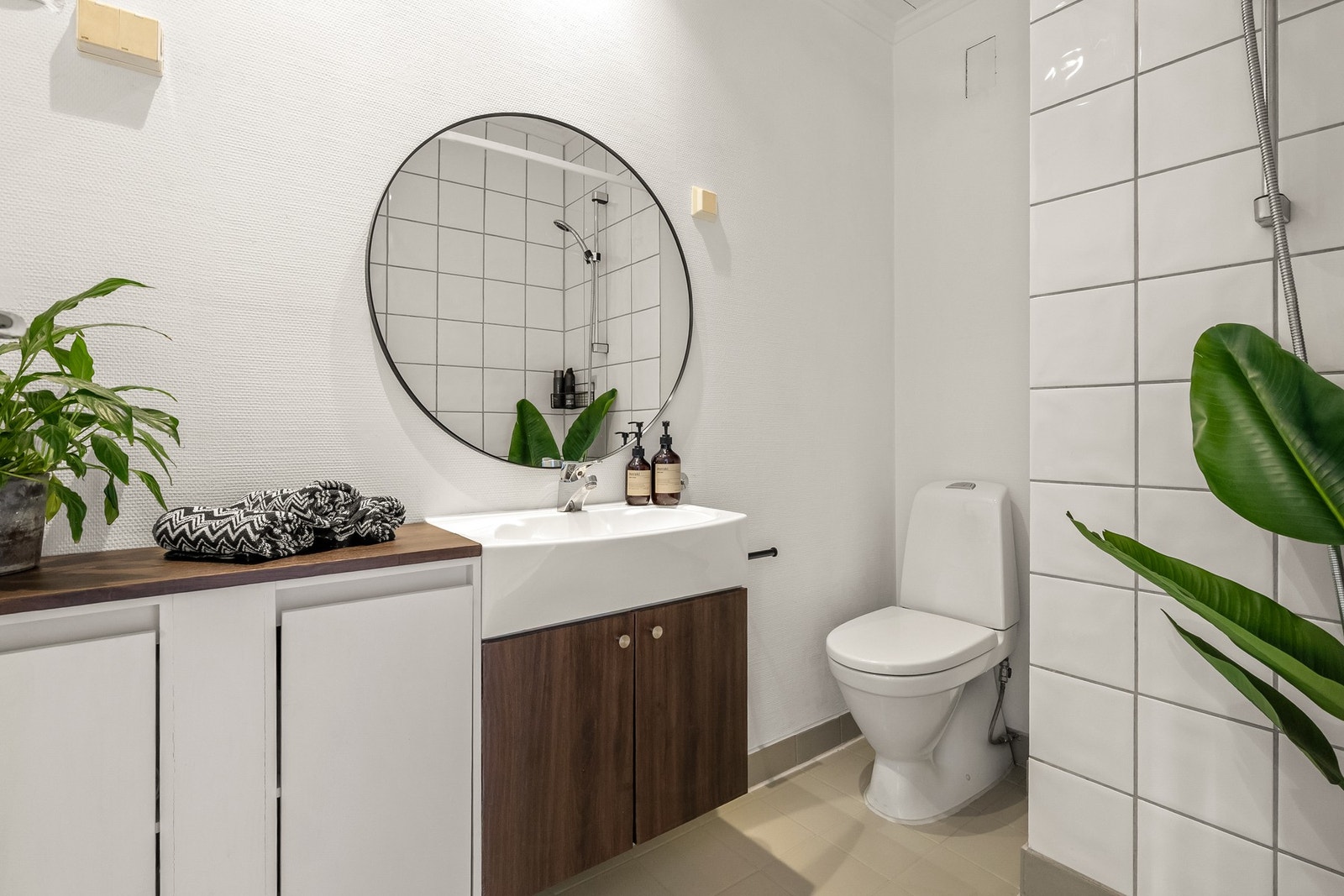 Lyst baderom med dusjhjørne, baderomsinnredning og toalett. Elektriske varmekabler på gulv og downlights i himling. Galleribilde