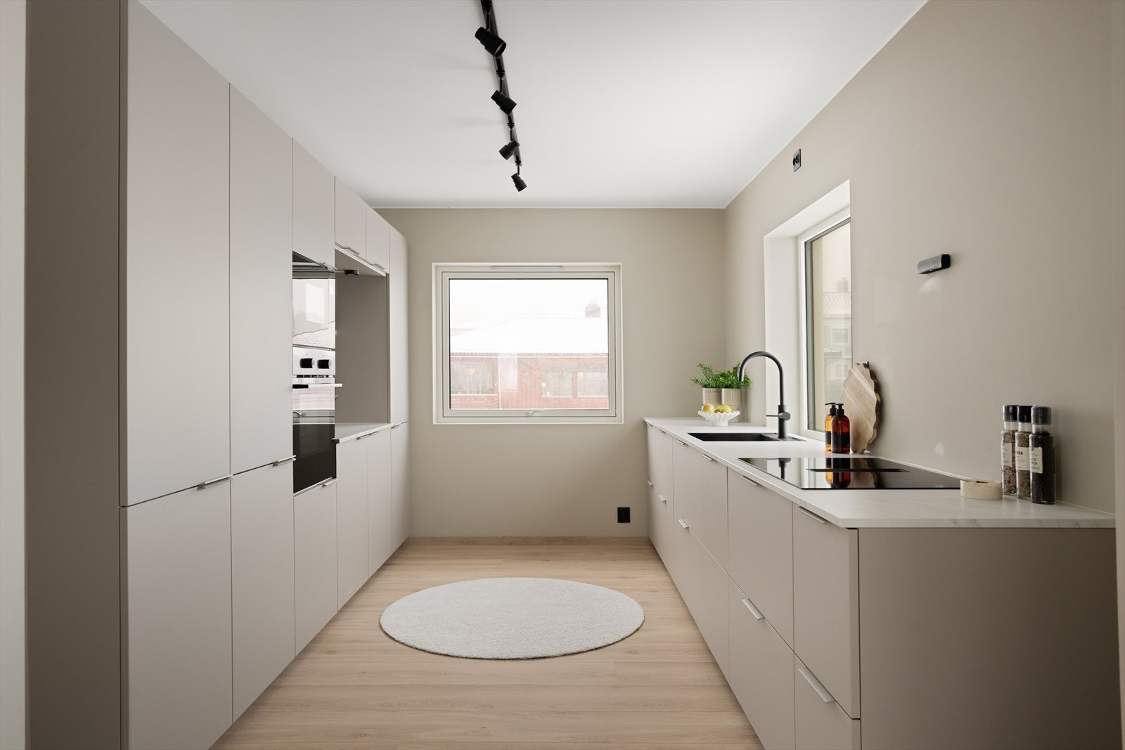 Stuen glir sømløst over i et svært romslig kjøkken fra Kvik, levert i delikate beige/grå fronter med hvit benkeplate. Galleribilde