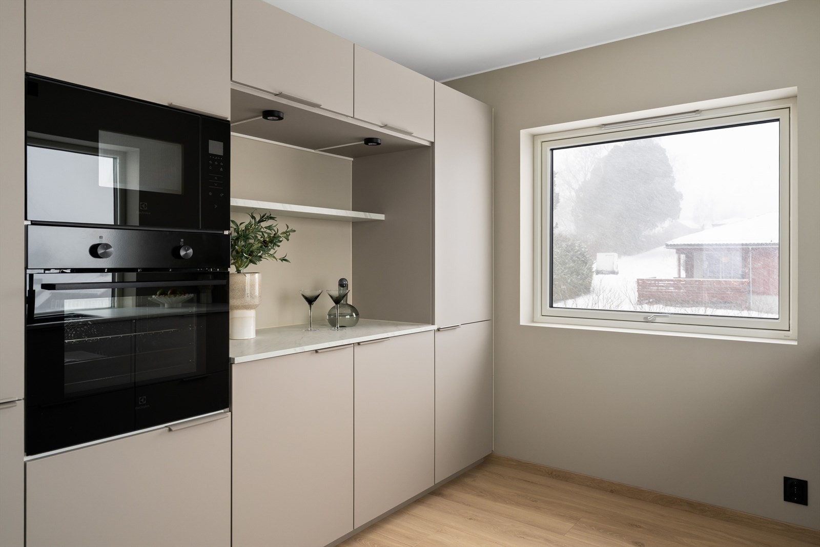 Kjøkkenet er både funksjonelt og stilfullt, med integrert platetopp, samt stekeovn og mikrobølgeovn plassert i praktisk ståhøyde. Galleribilde