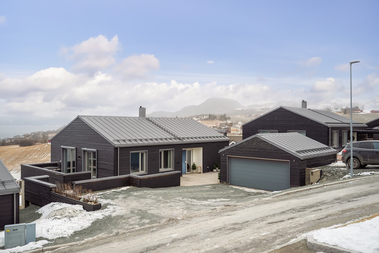 Dobbelgarasje og stor gårdsplass med plass til flere besøkende biler. Det er også parkering tilhørende eiendommen på oversiden av garasjen. Galleribilde