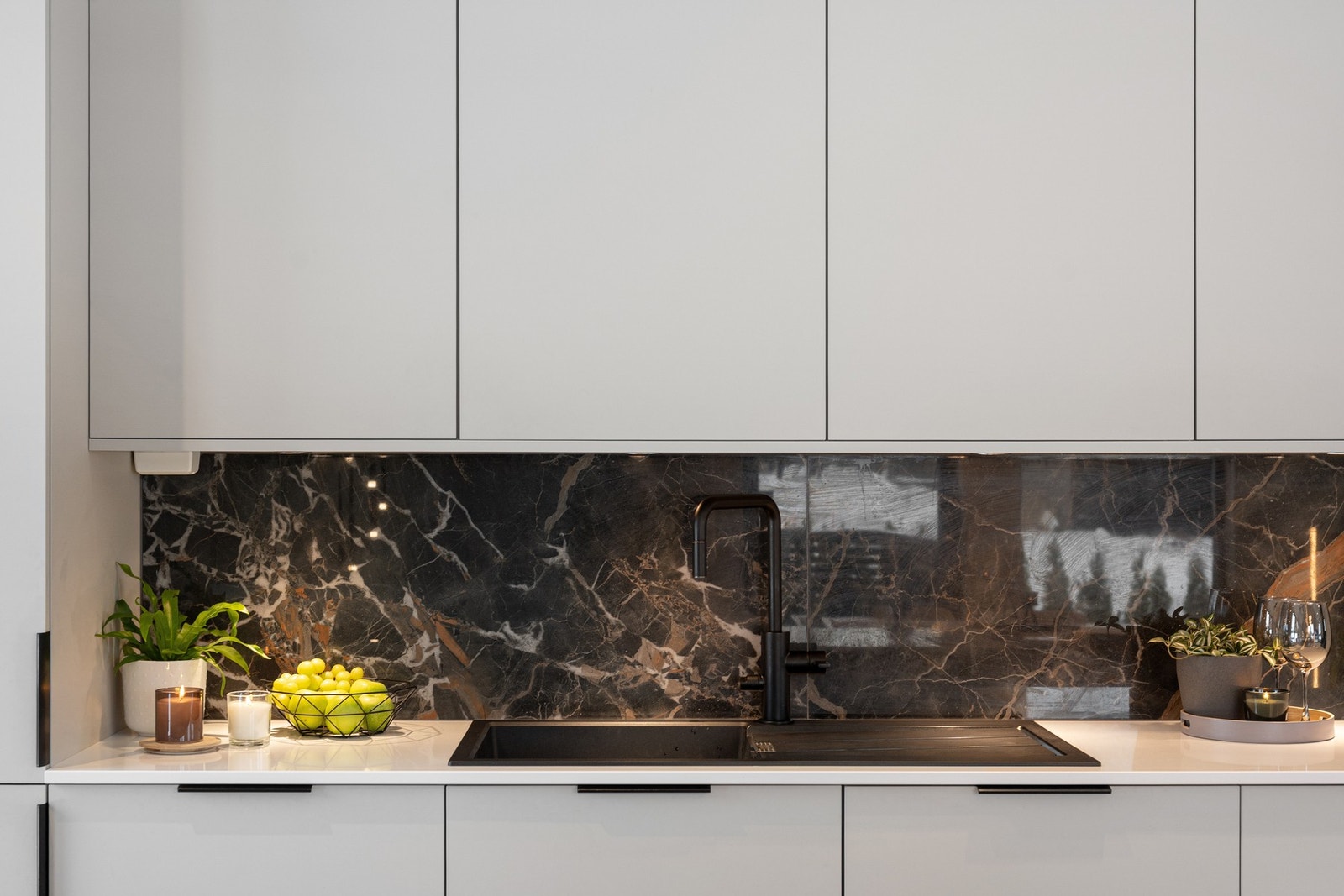 Kjøkkenet har et moderne uttrykk med slette fronter, benkeplate av stein og lekre fliser under overskapene. Galleribilde